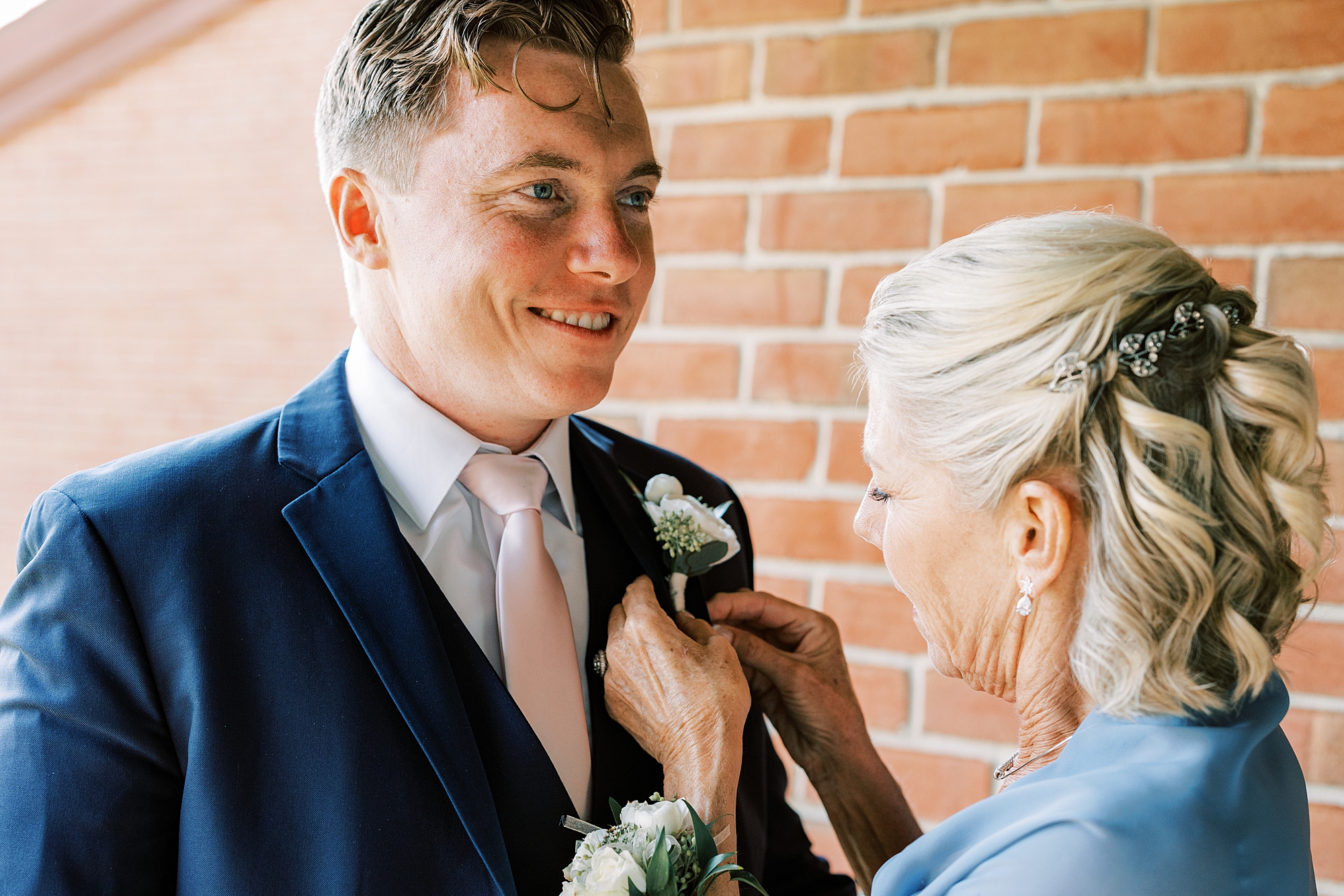 mother pins boutonniere on groom's chest during PA wedding day