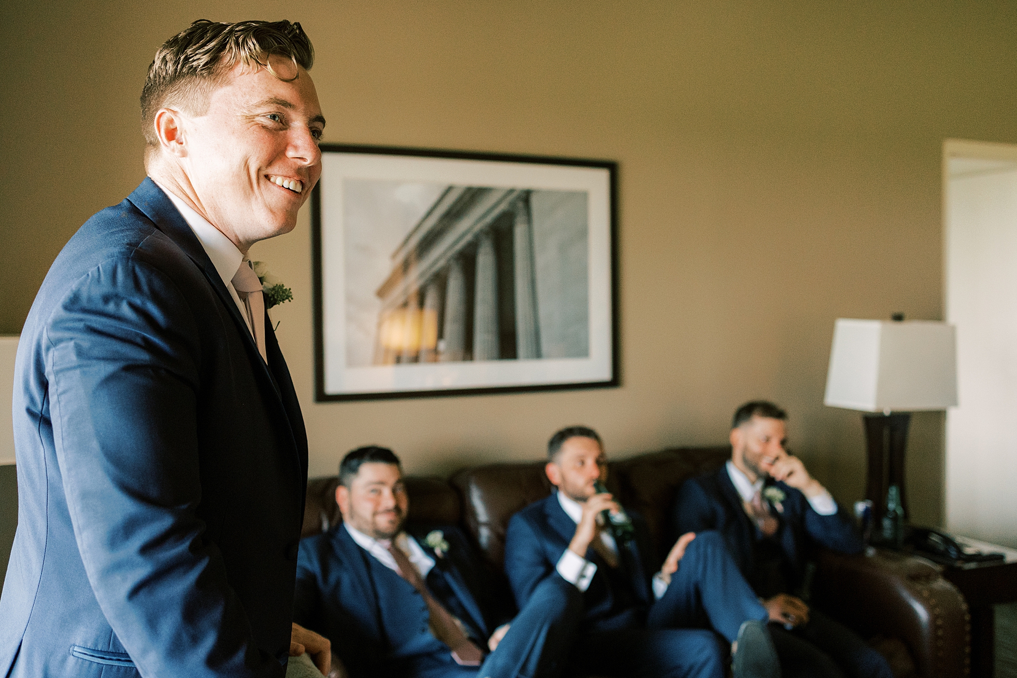 groom laughs with groomsmen in navy suits