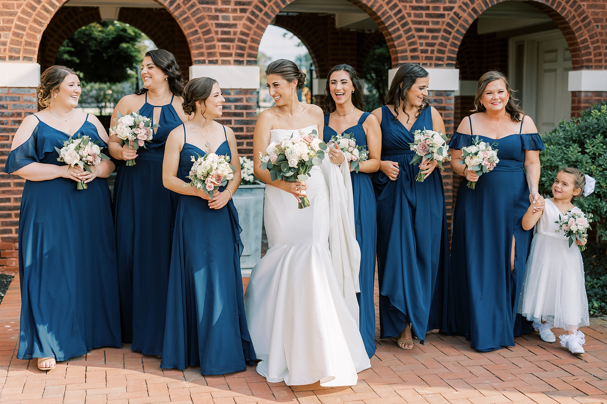 bride walks with bridesmaids in navy blue gowns in Philadelphia PA