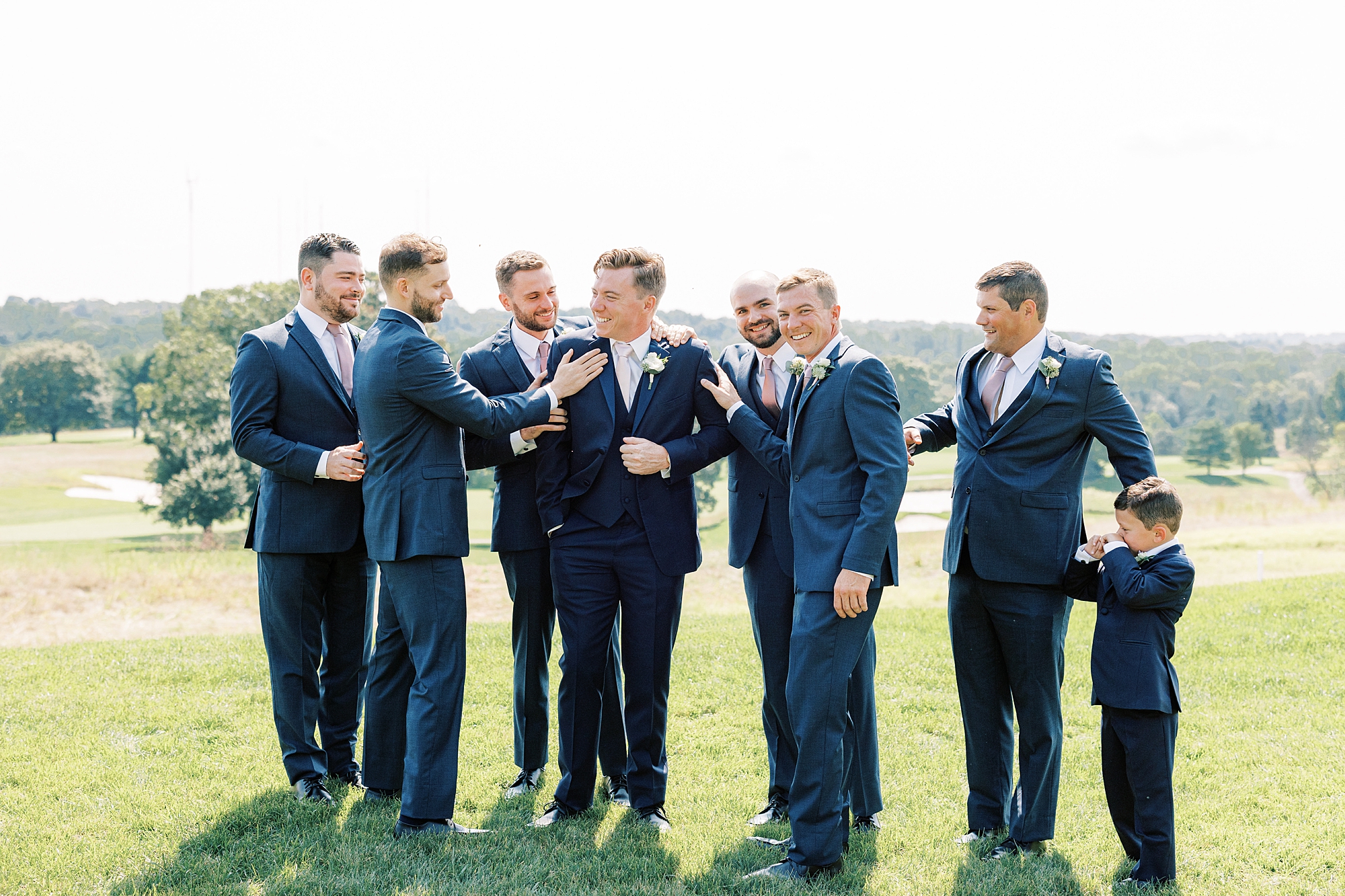 groom walks with groomsmen in navy suits in Philadelphia PA