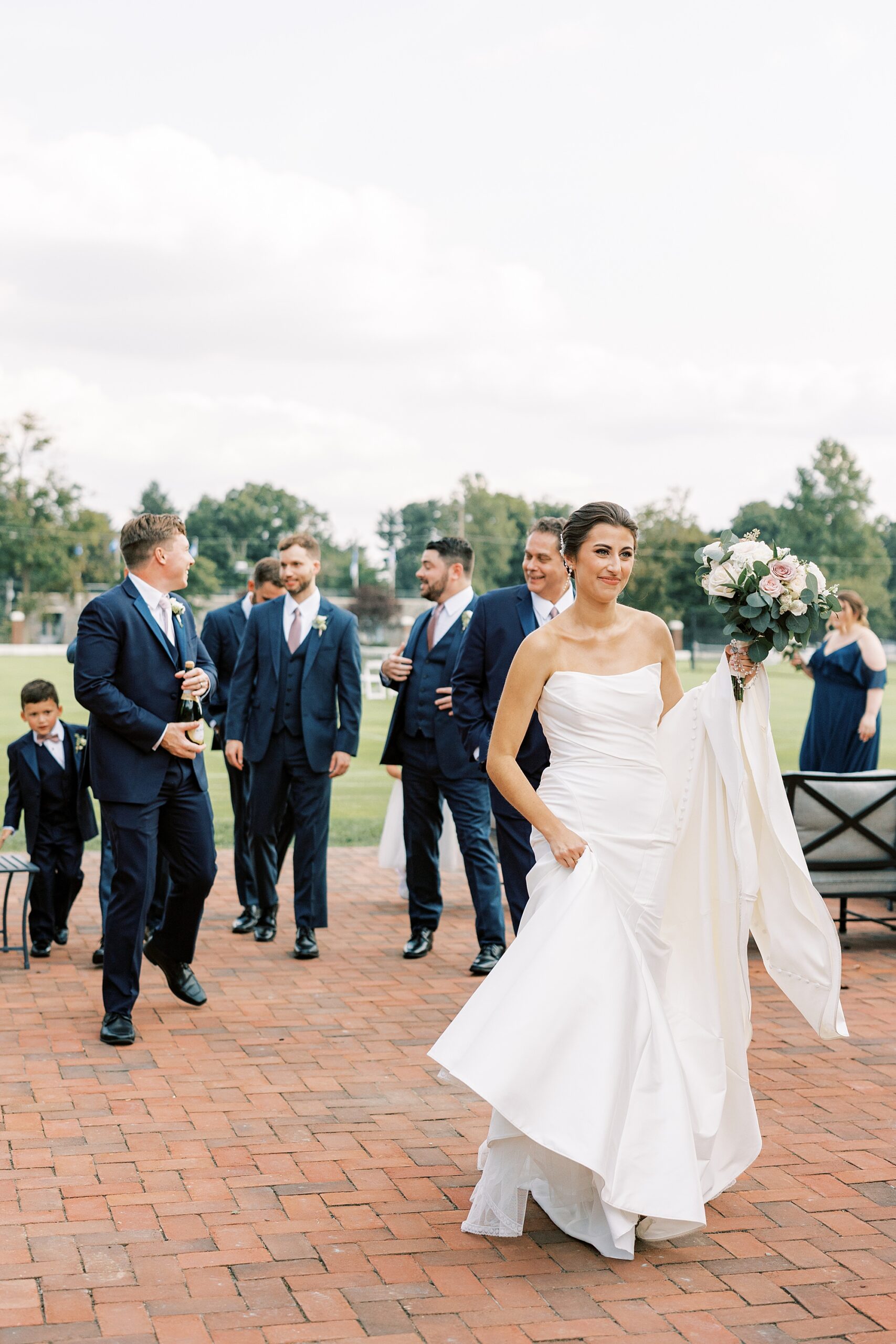 bride walks in front of groomsmen on brick patio at the Philadelphia Cricket Club