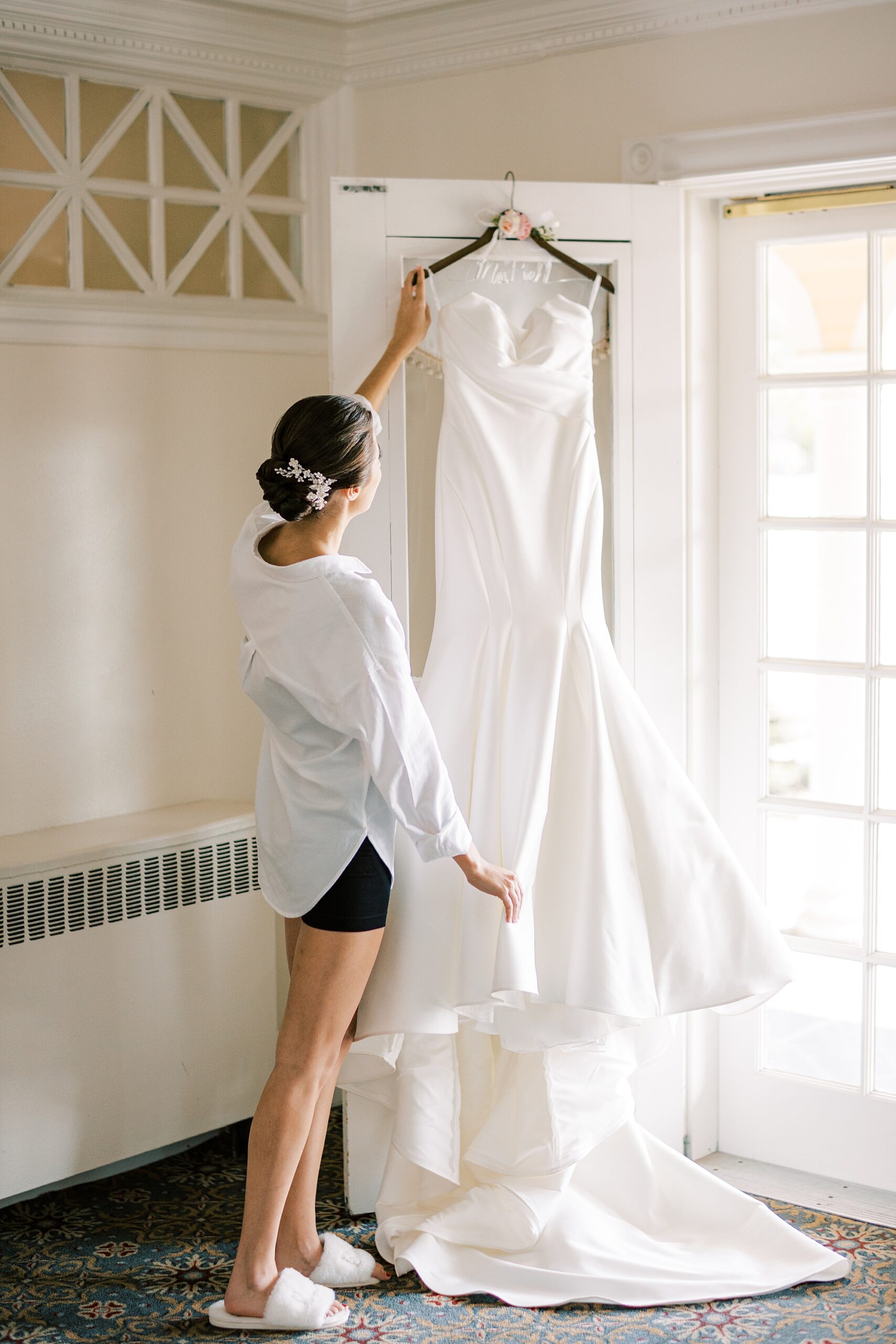bride looks at wedding dress hanging on front door of the Philadelphia Cricket Club