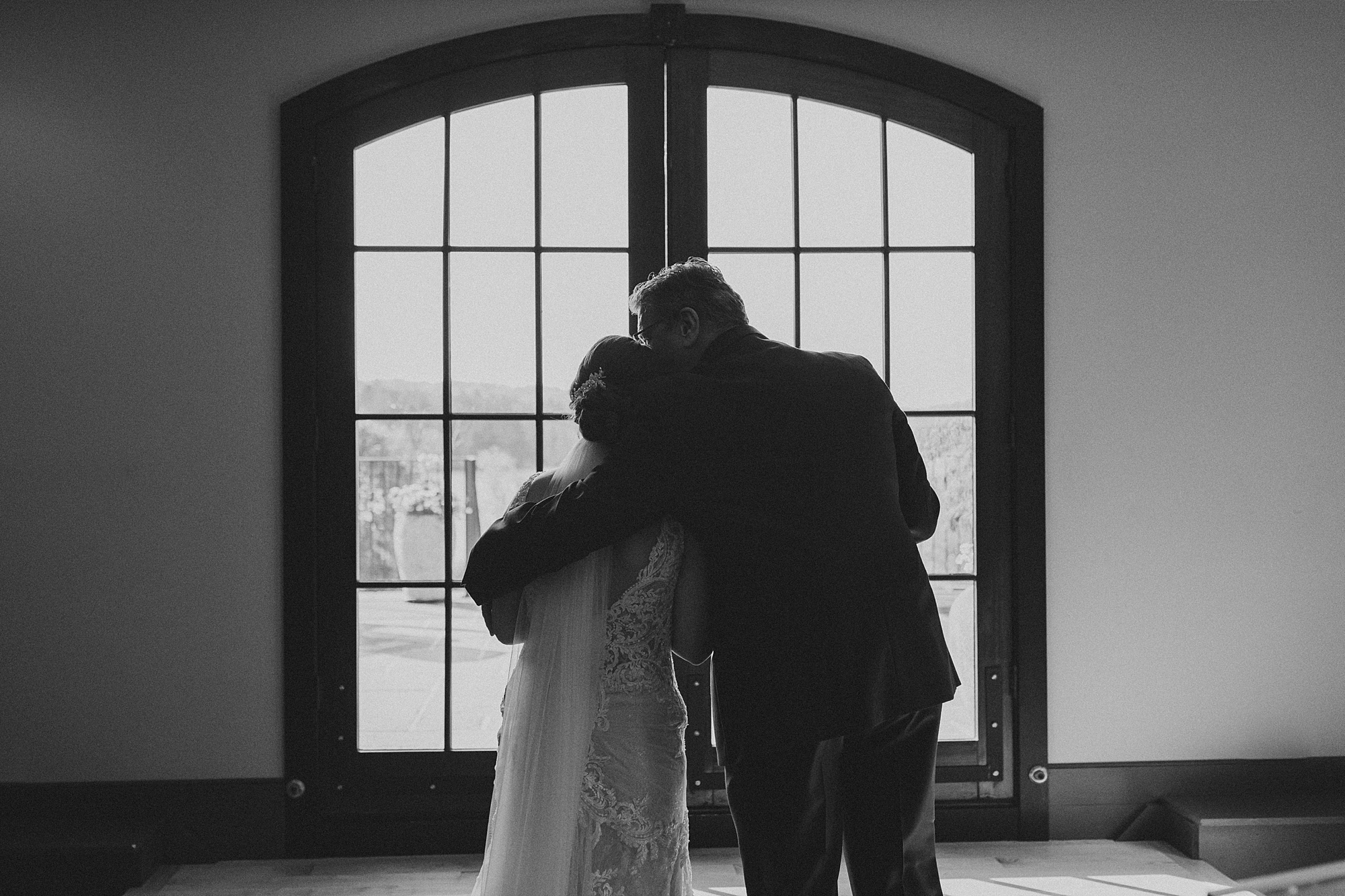 dad hugs bride near window before walking out for ceremony 