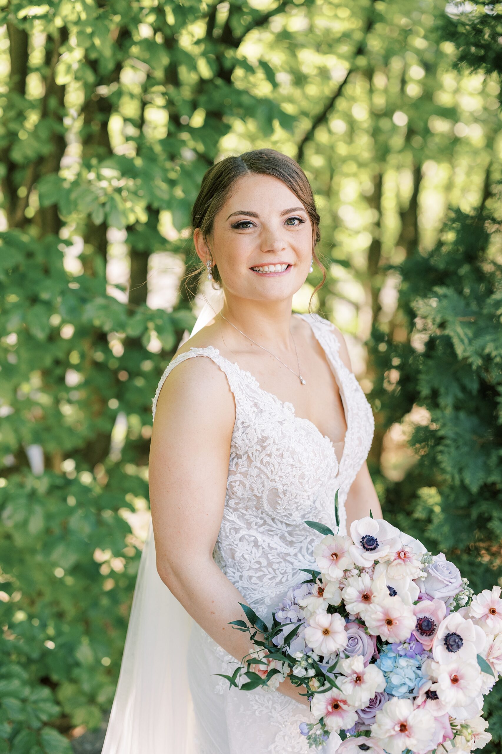 bride smiles holding bouquet of pink and white flowers for spring wedding 