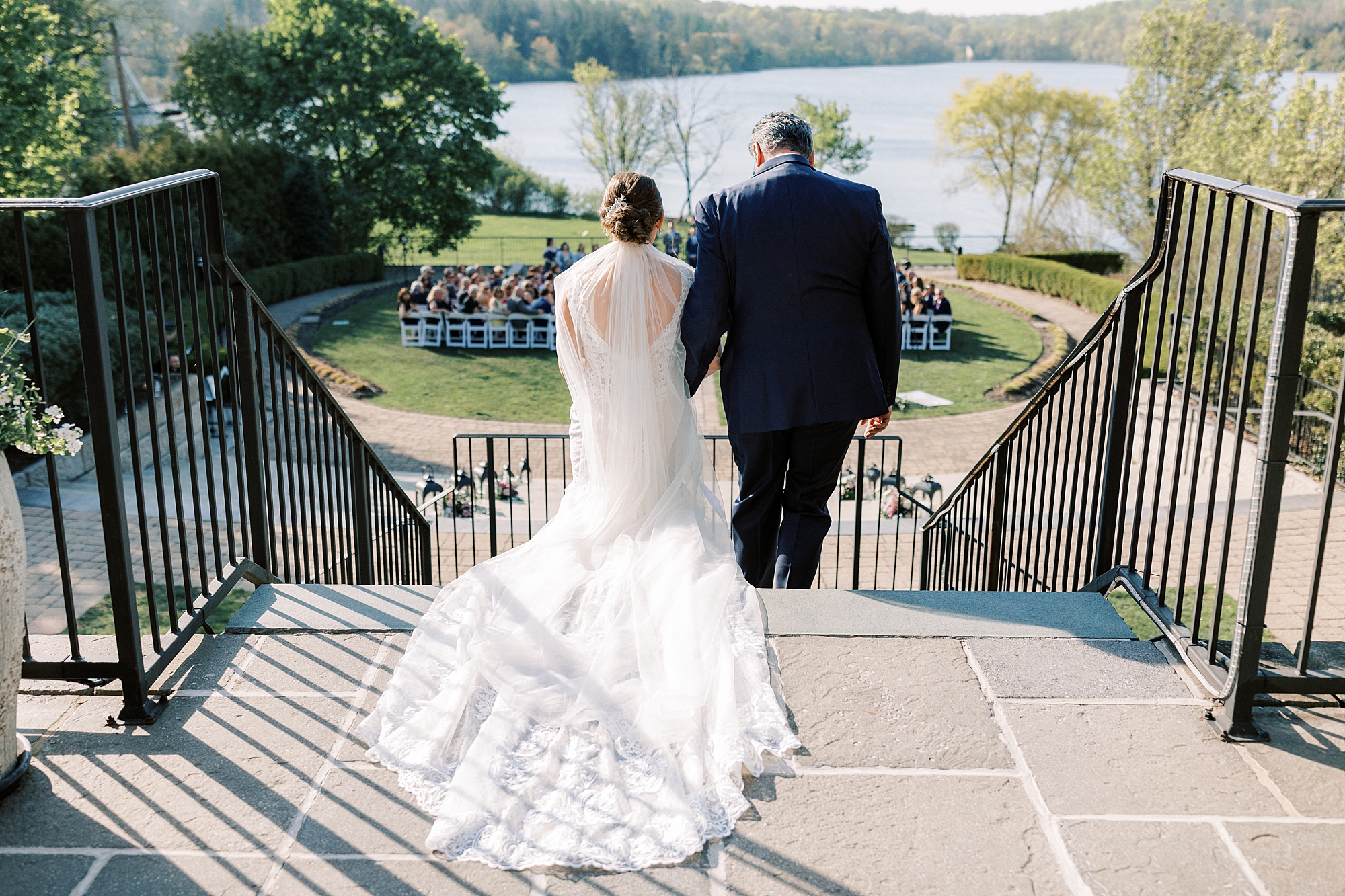 bride and father walk down steps to ceremony on lawn at Lake House Inn