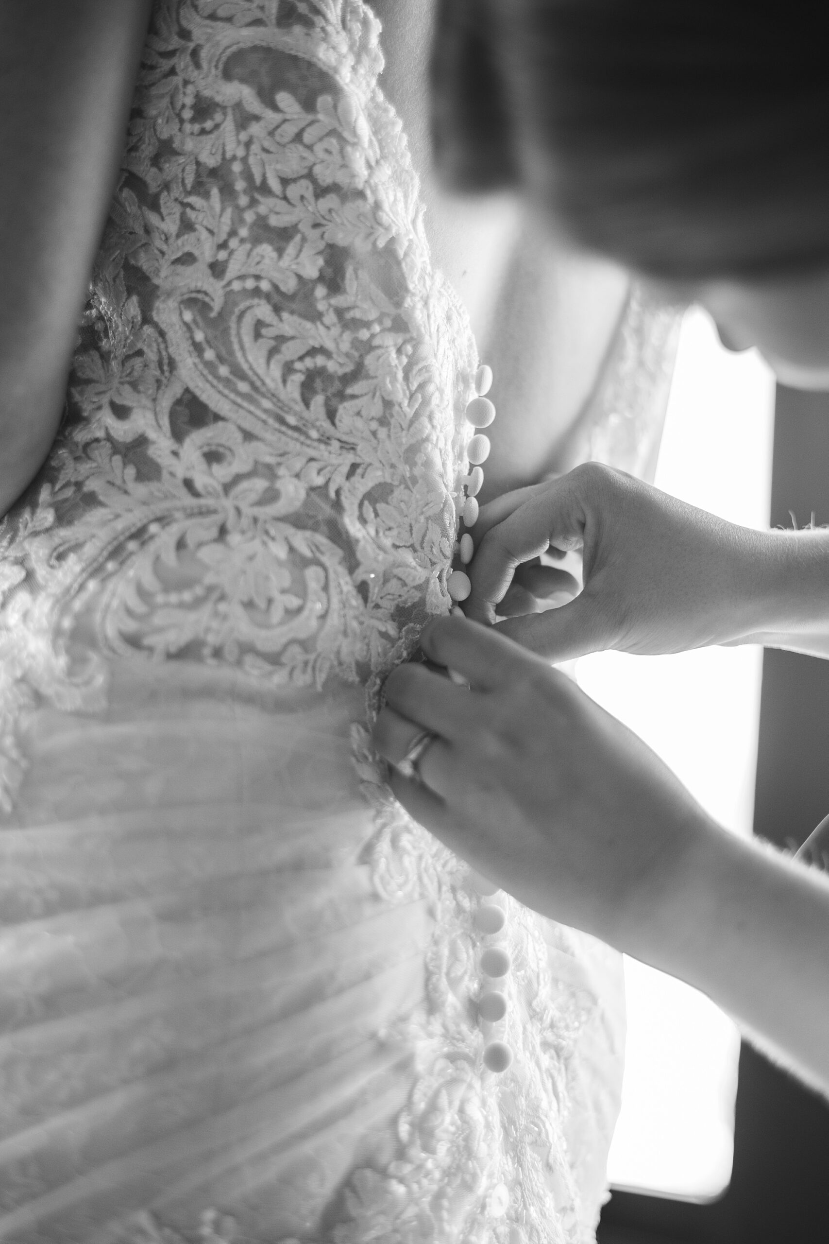 black and white photo of bridesmaid buttoning wedding dress