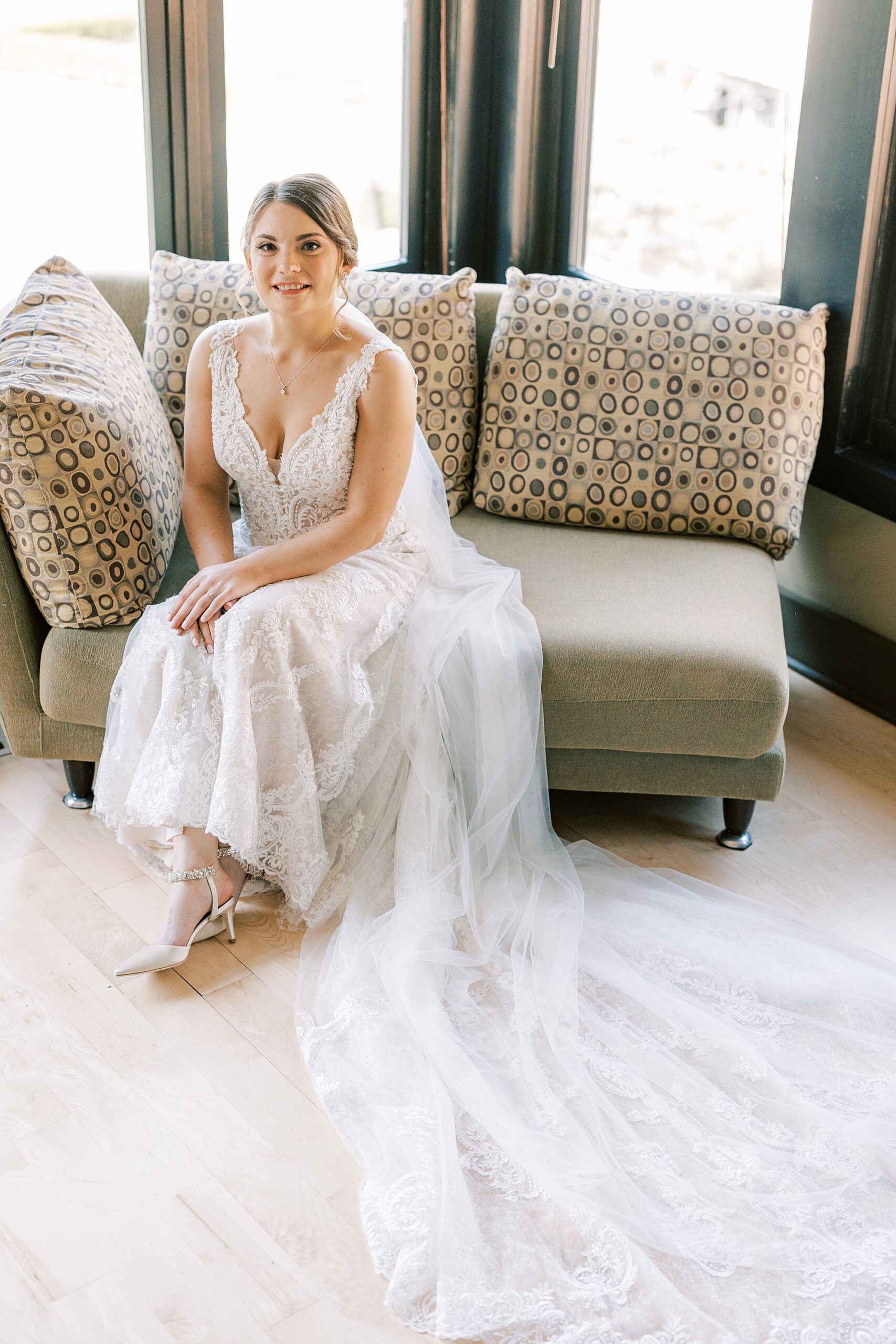 bride sits on tan couch in bridal suite at Lake House Inn