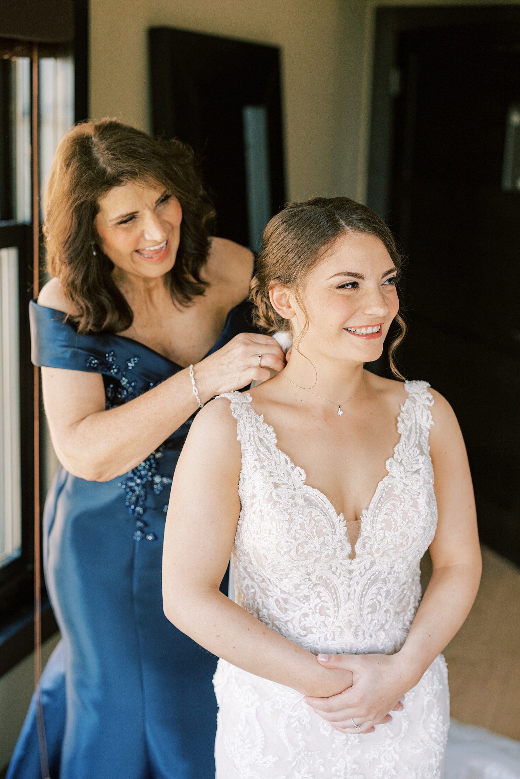 mother in blue dress helps bride with jewelry before PA wedding 