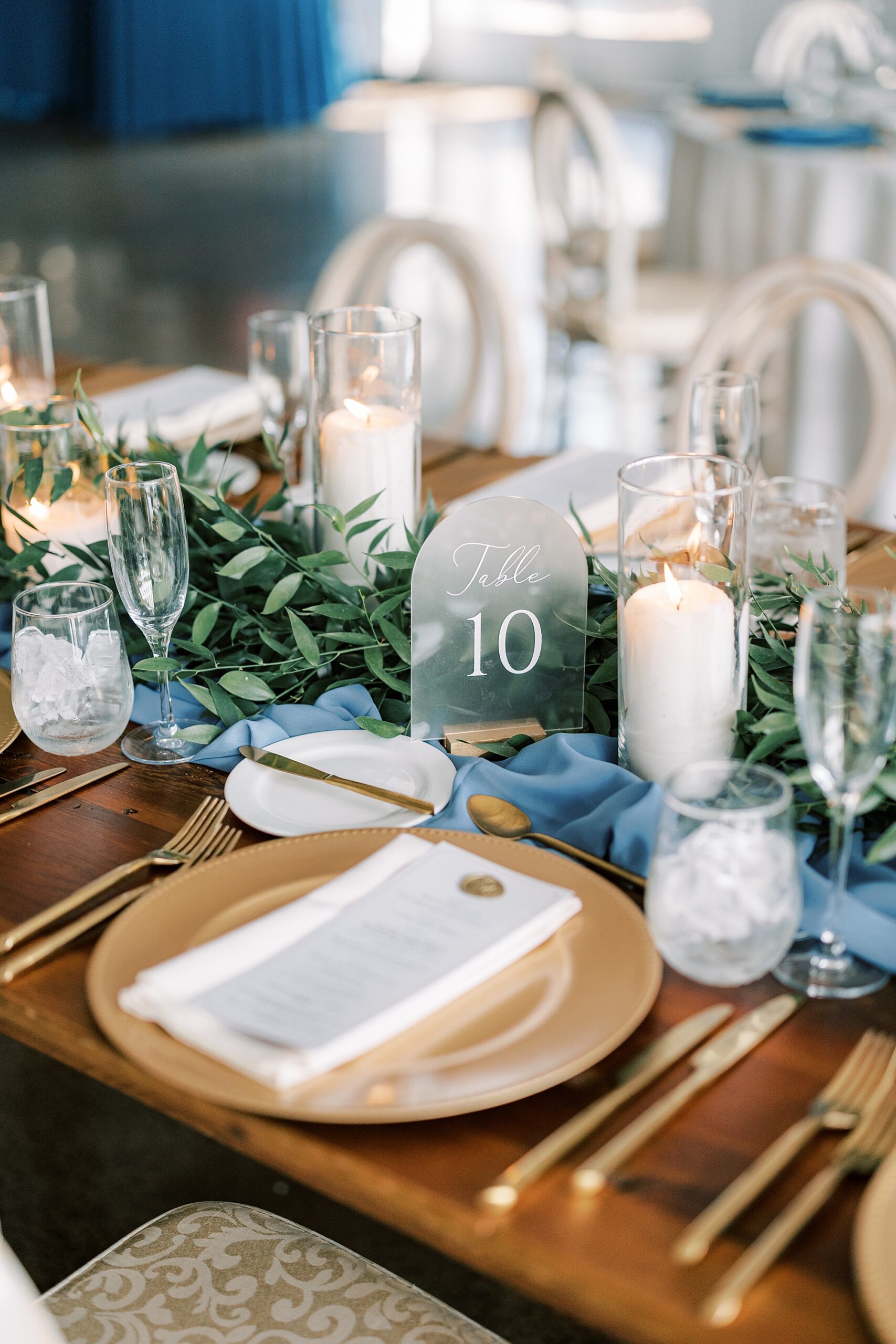 place setting with gold plate, white candle, acrylic table number sign 