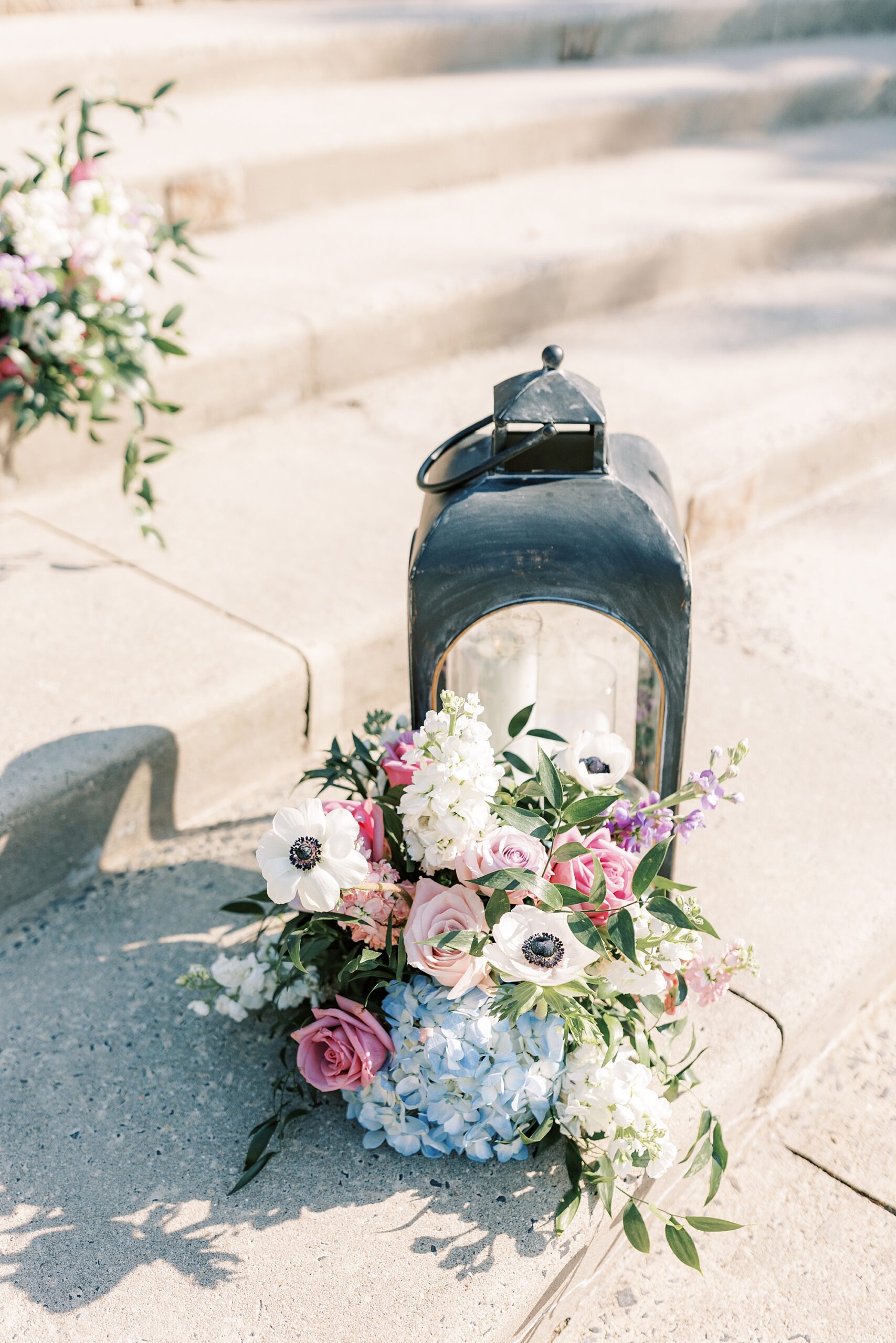 lantern rests on steps of Lake House Inn with purple and white flowers 