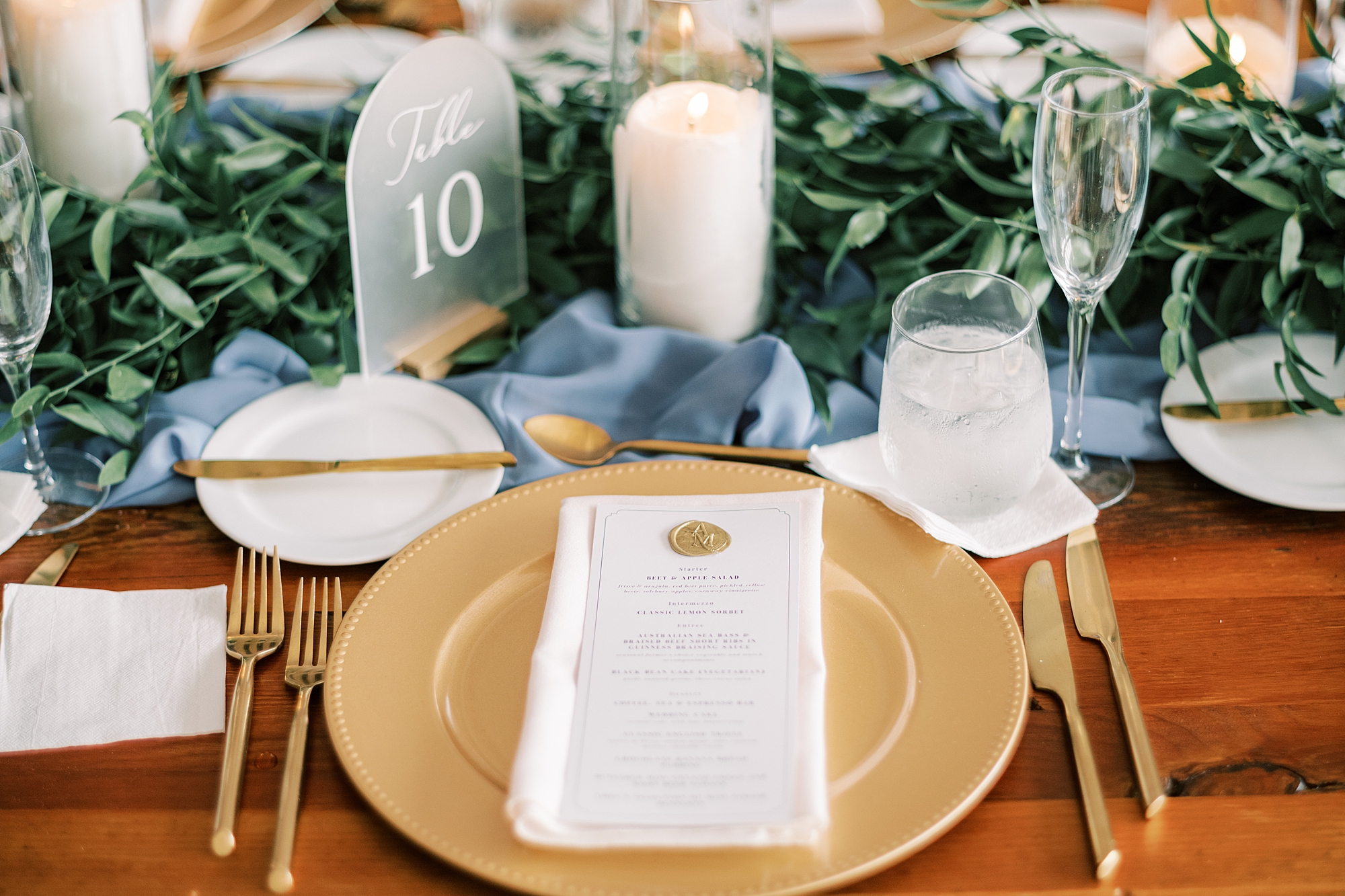 place setting with gold plate, white menu card, and white candles 