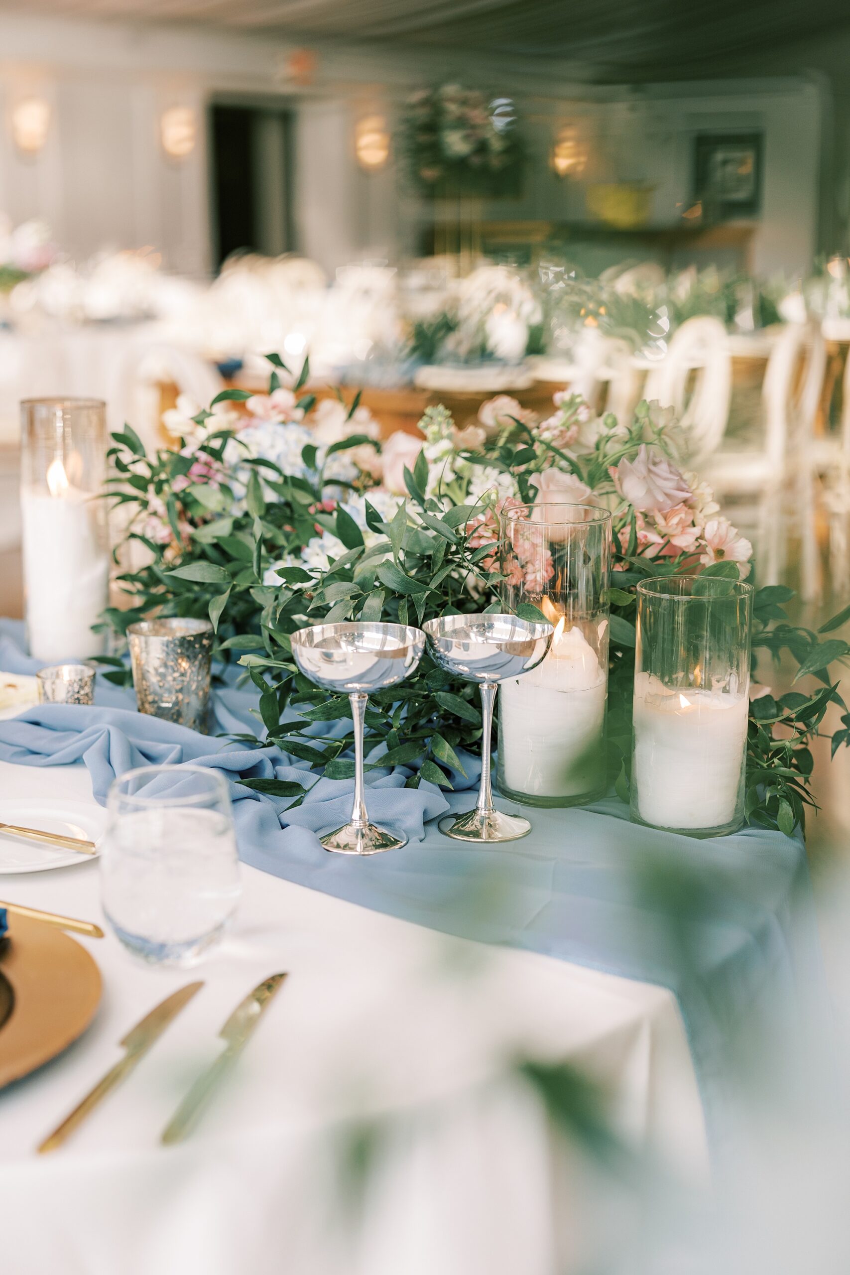 wine glasses rest by white candles ands greenery table runner for spring wedding reception at Lake House Inn