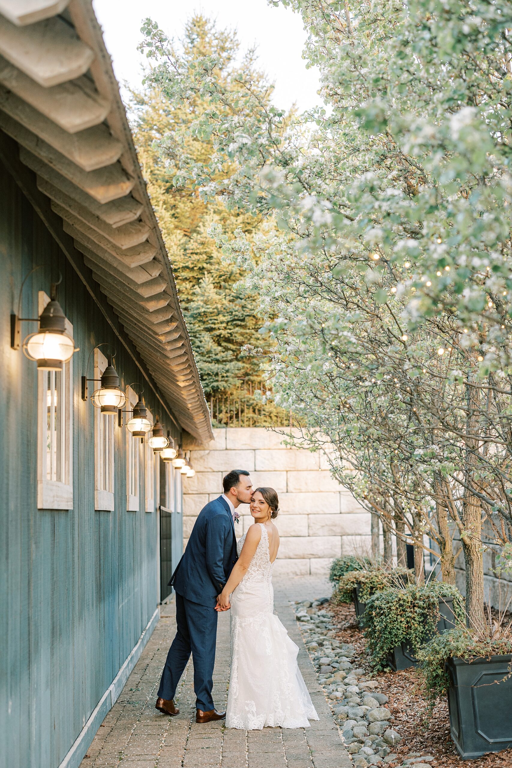 groom leans to kiss bride's cheek outside Lake House Inn