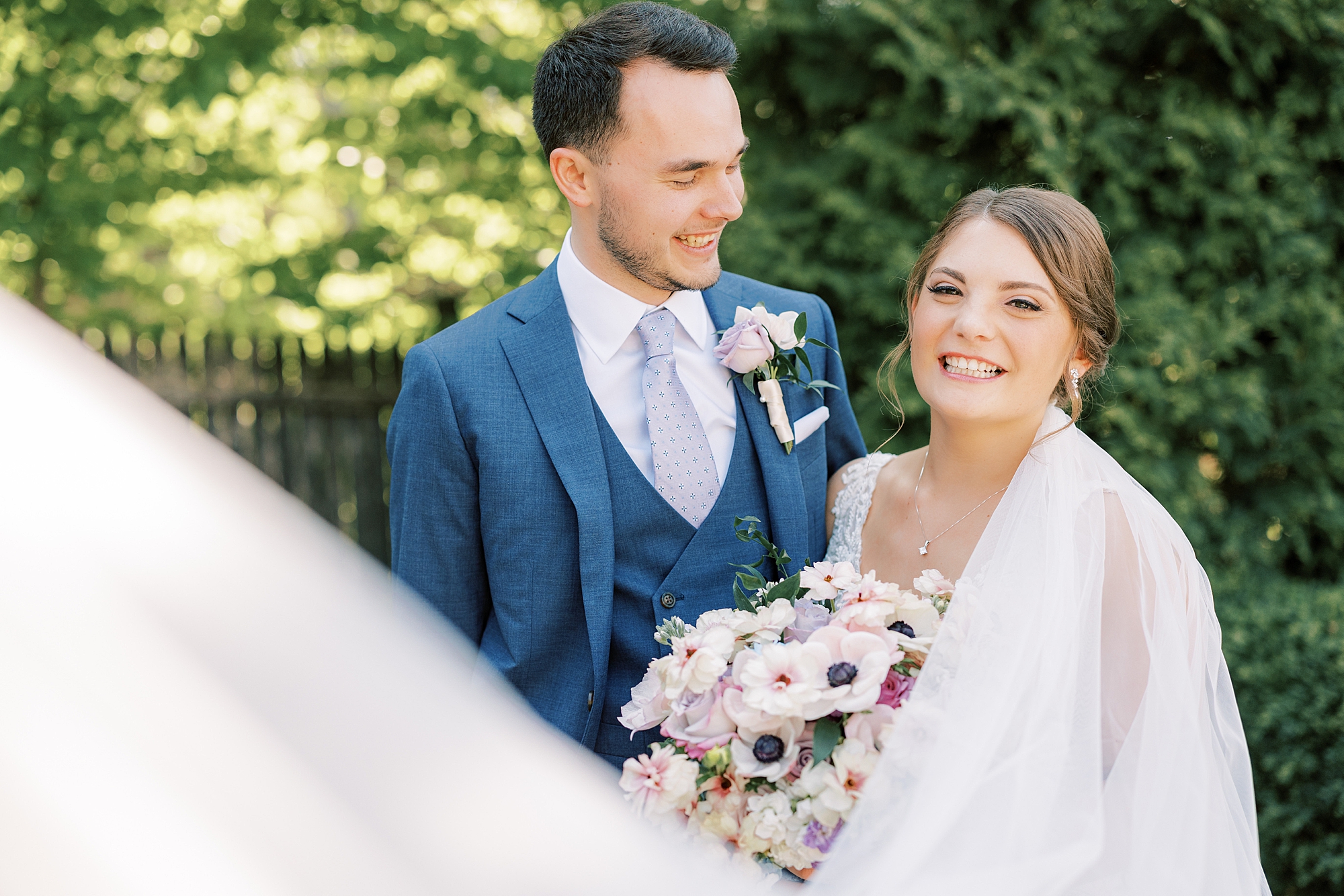 groom turns to look at bride smiling with veil floating around them at Lake House Inn