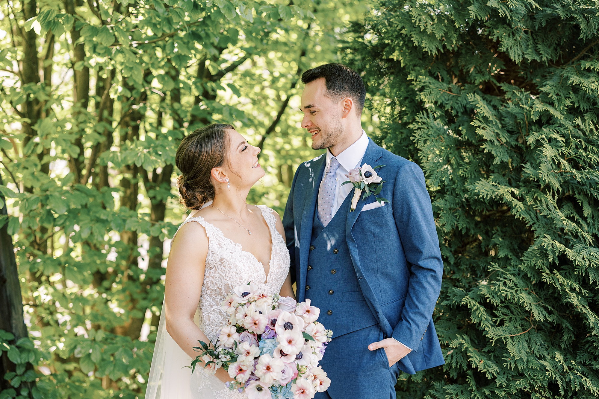 bride and groom smile together hugging between trees at Lake House Inn