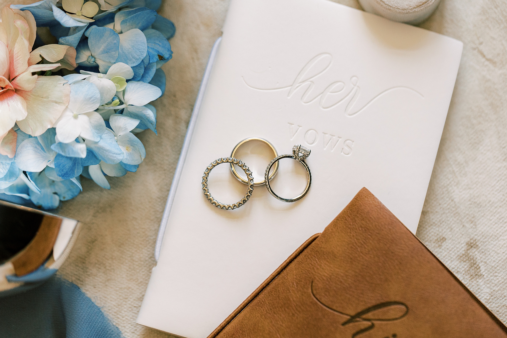 wedding bands lay on ivory vow booklet for spring wedding at Lake House Inn