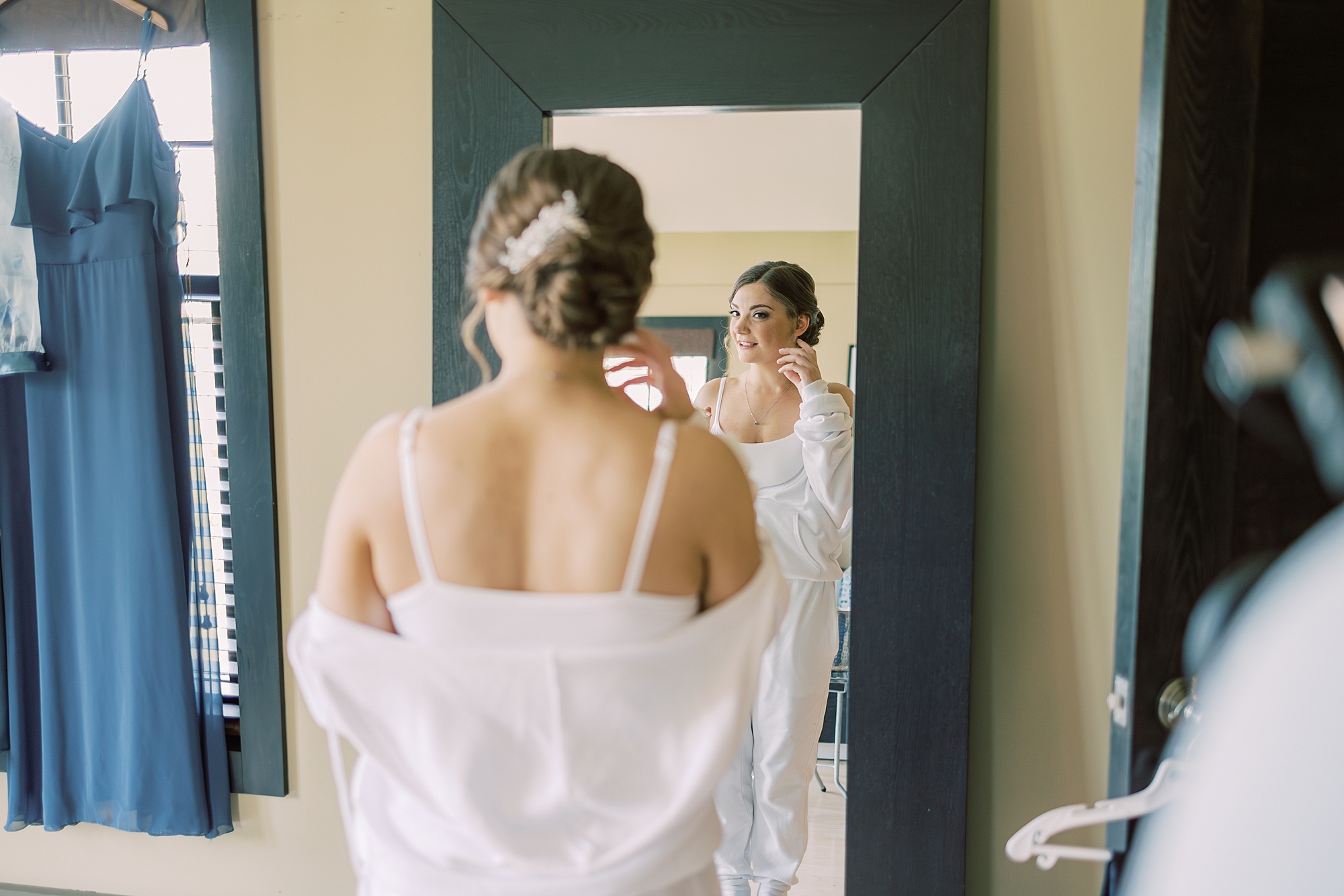 bride looks at herself in mirror on morning of wedding day