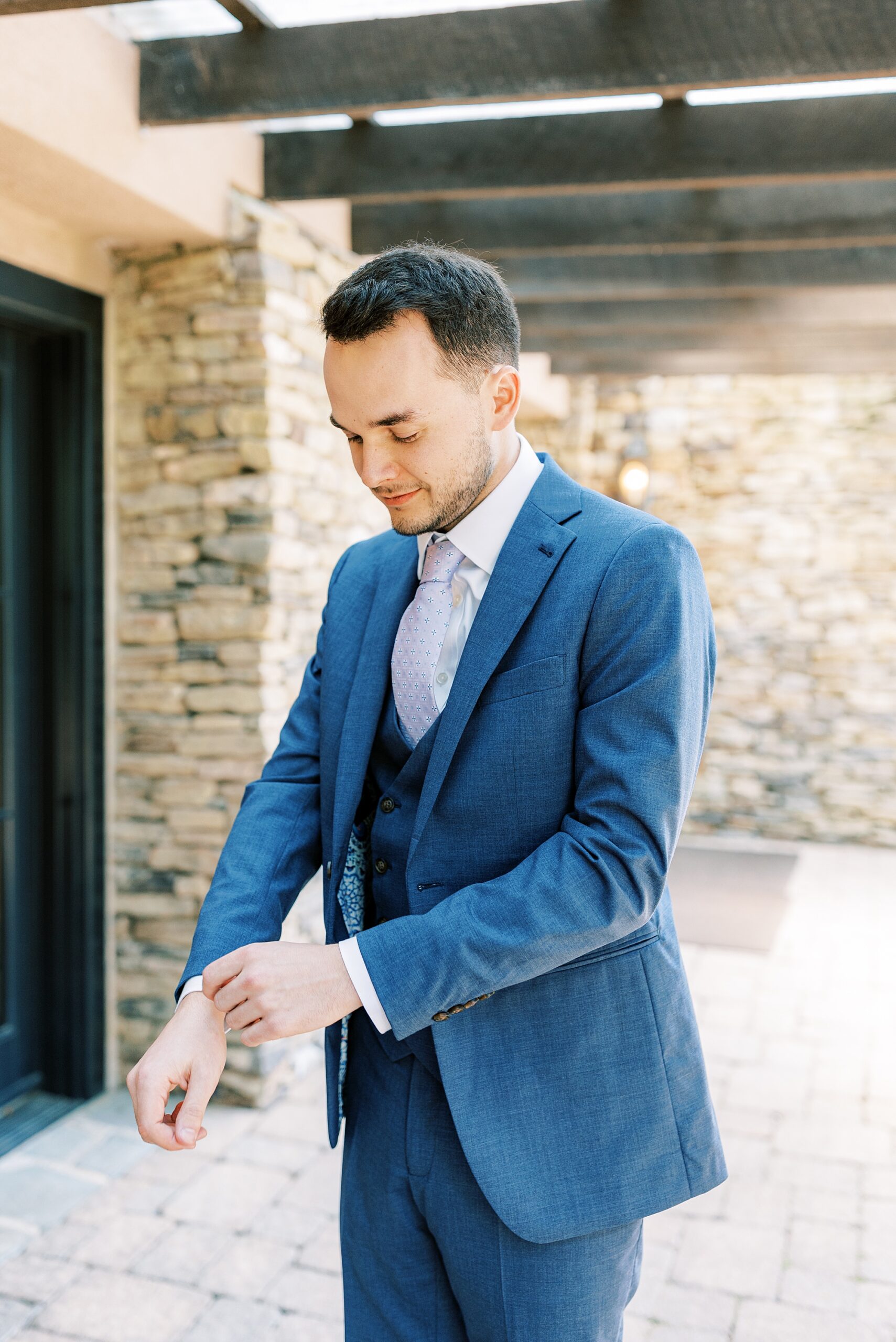 groom adjusts sleeves of blue suit at Lake House Inn