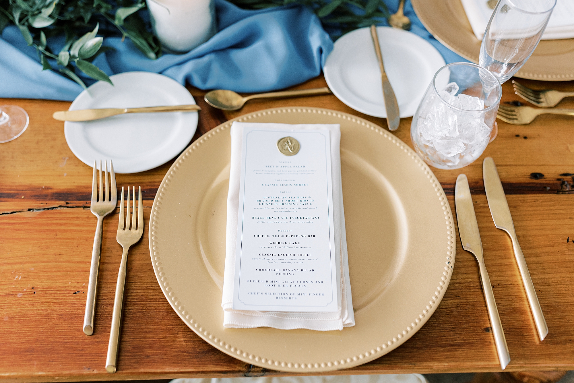 place setting with gold plate, menu with gold wax seal and gold silverware 