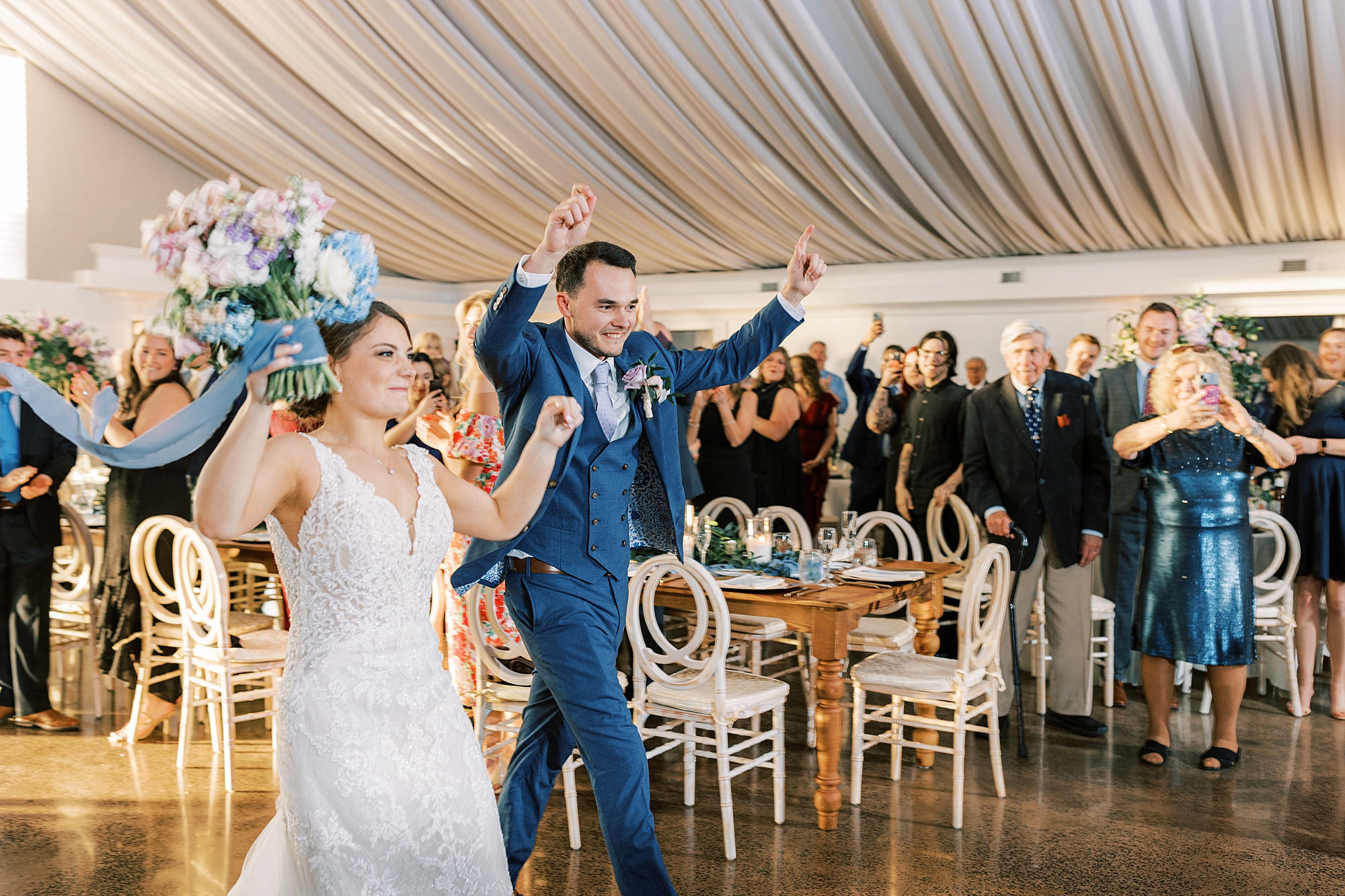 bride and groom cheer walking into spring wedding reception 