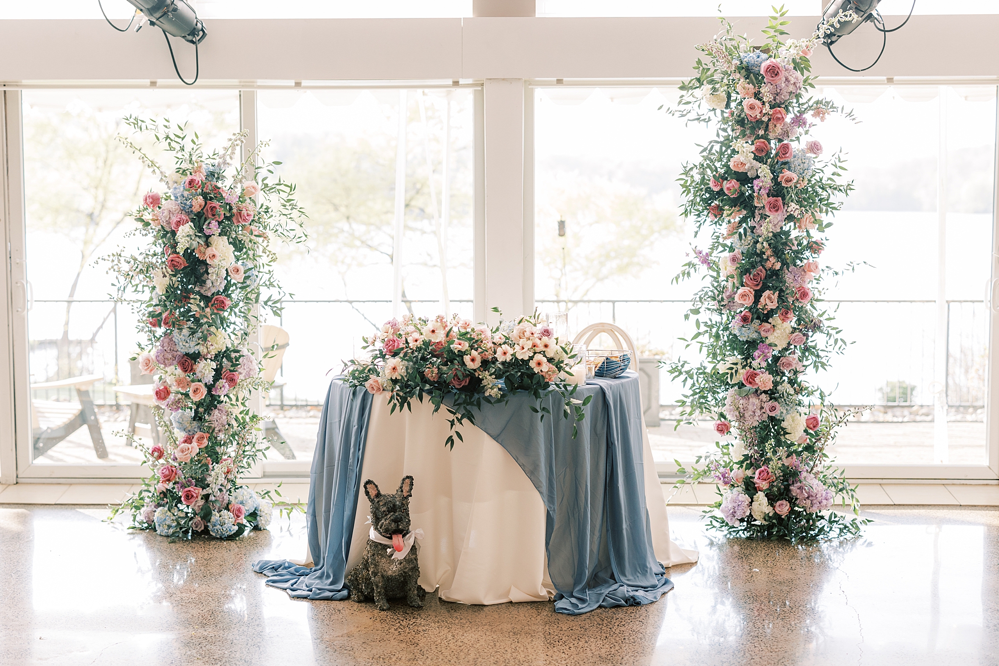 sweetheart table with floral installations beside it and blue table cloth 