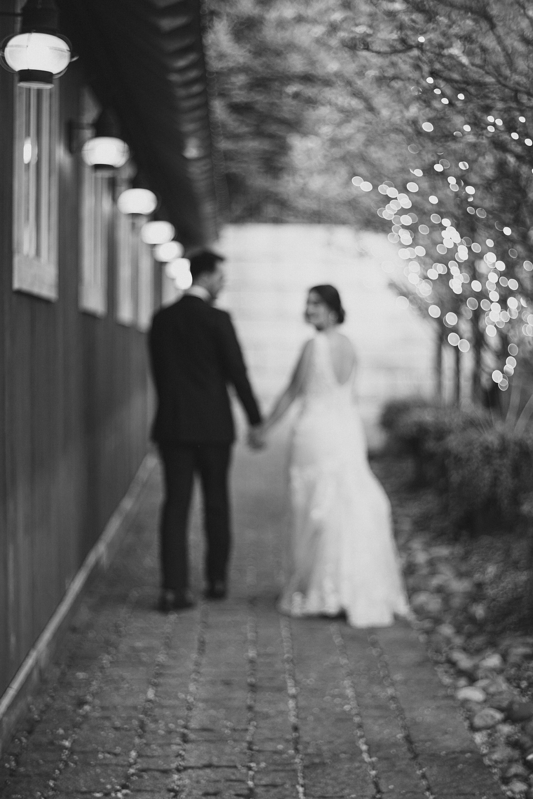 bride and groom hold hands walking away from Lake House Inn