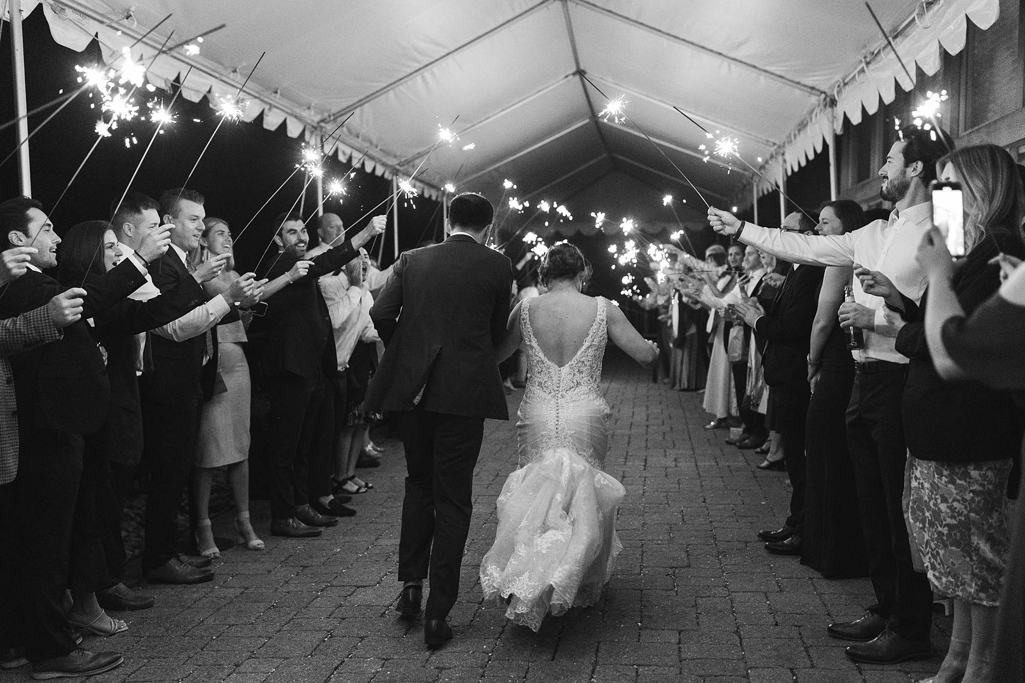 bride and groom hold hands leaving Perkasie PA wedding reception through sparklers 