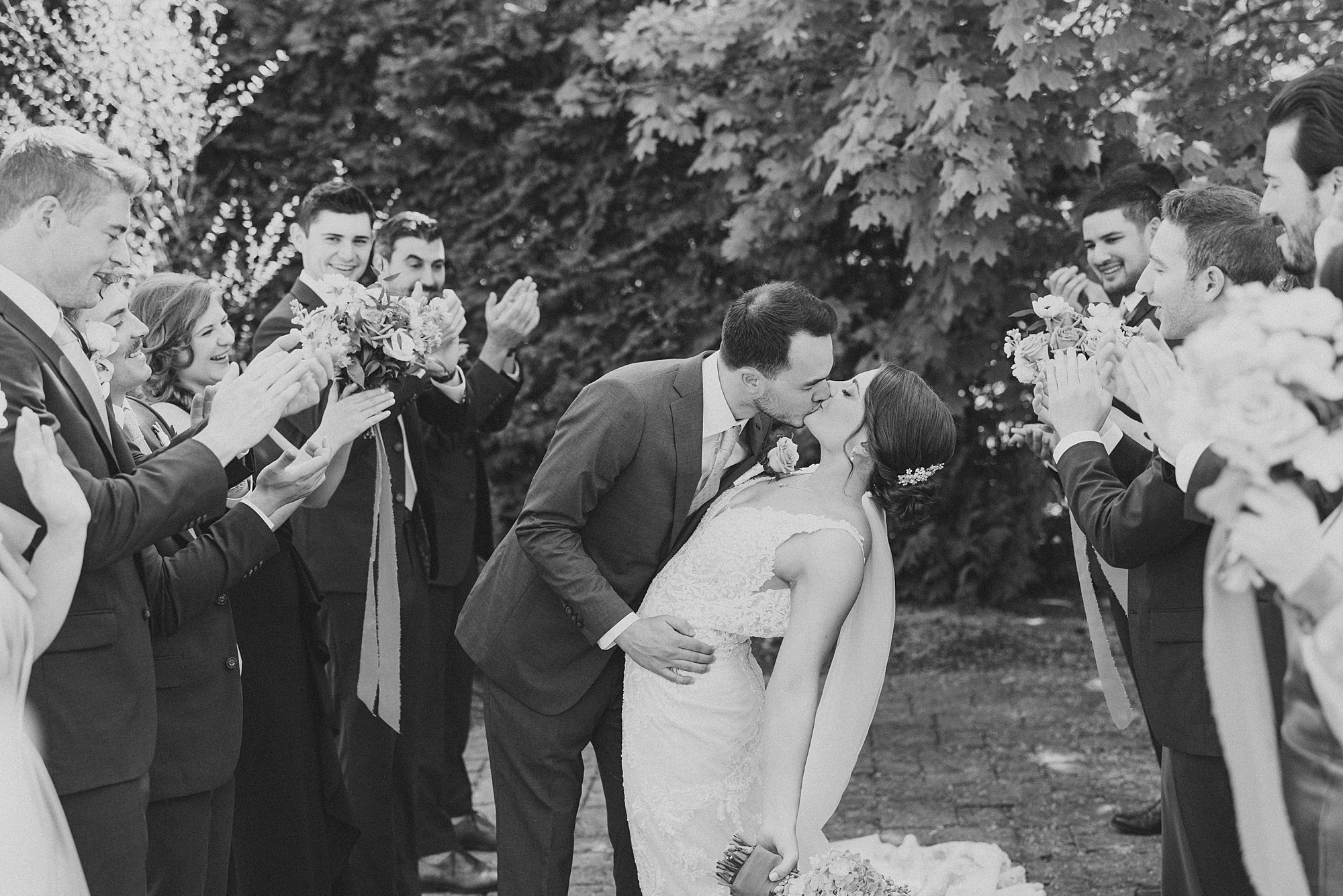 groom kisses bride dipping her while bridal party cheers