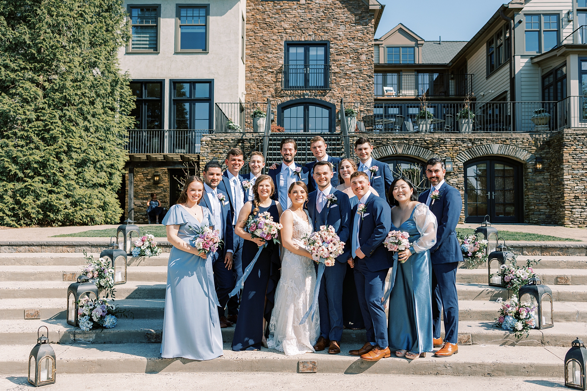 bride and groom hug on steps with wedding party around them at Lake House Inn