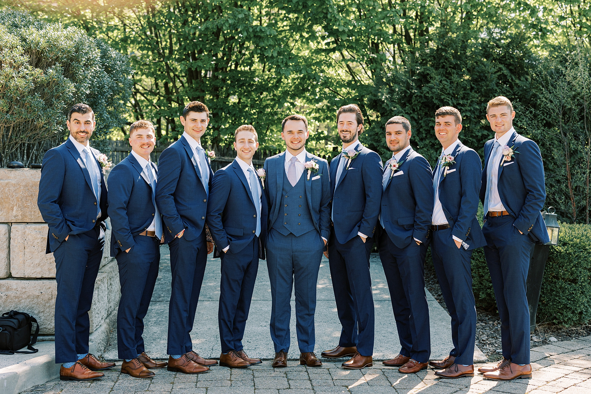 groom stands with groomsmen in navy suits