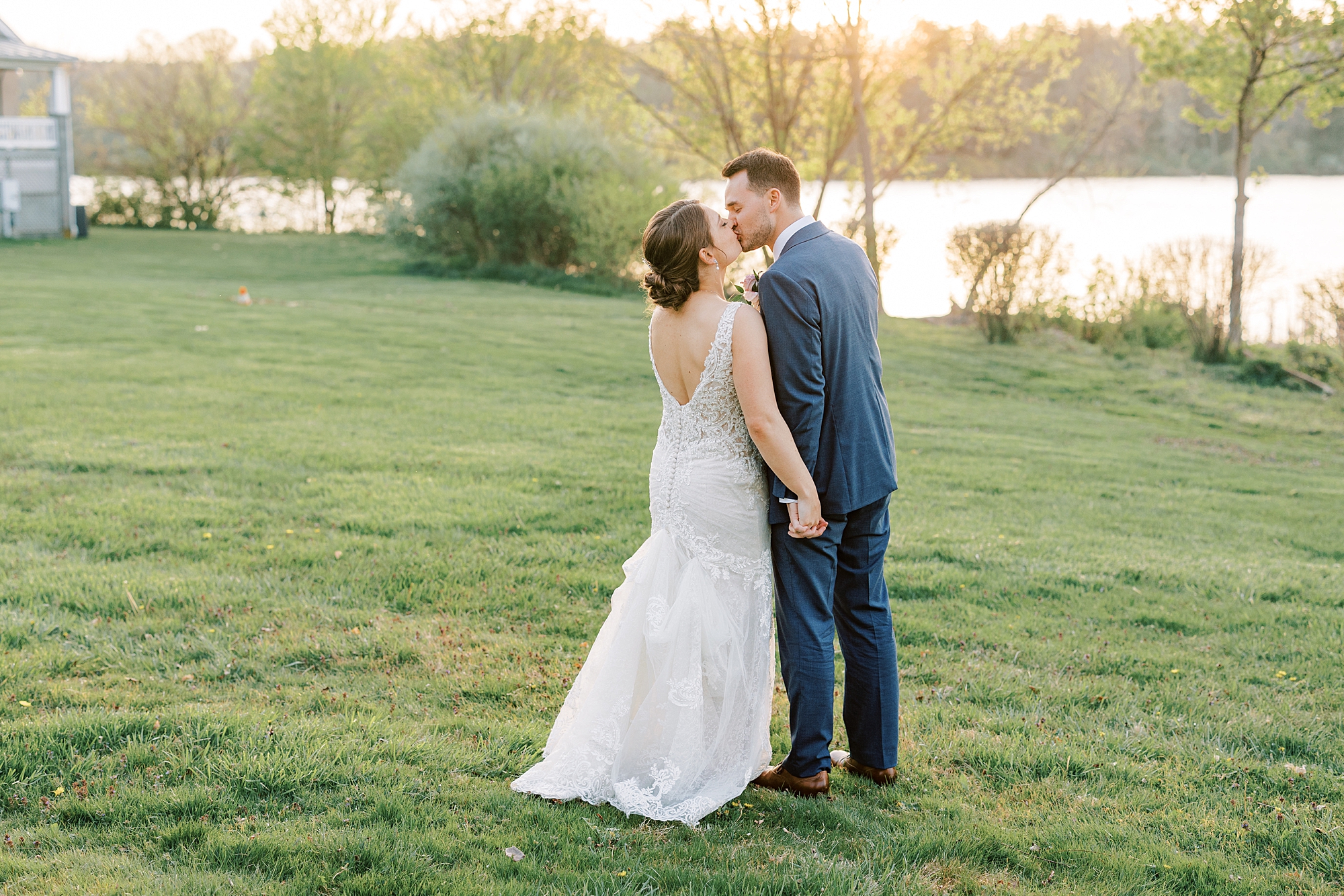 newlyweds kiss during sunset portraits on lawn at Lake House Inn