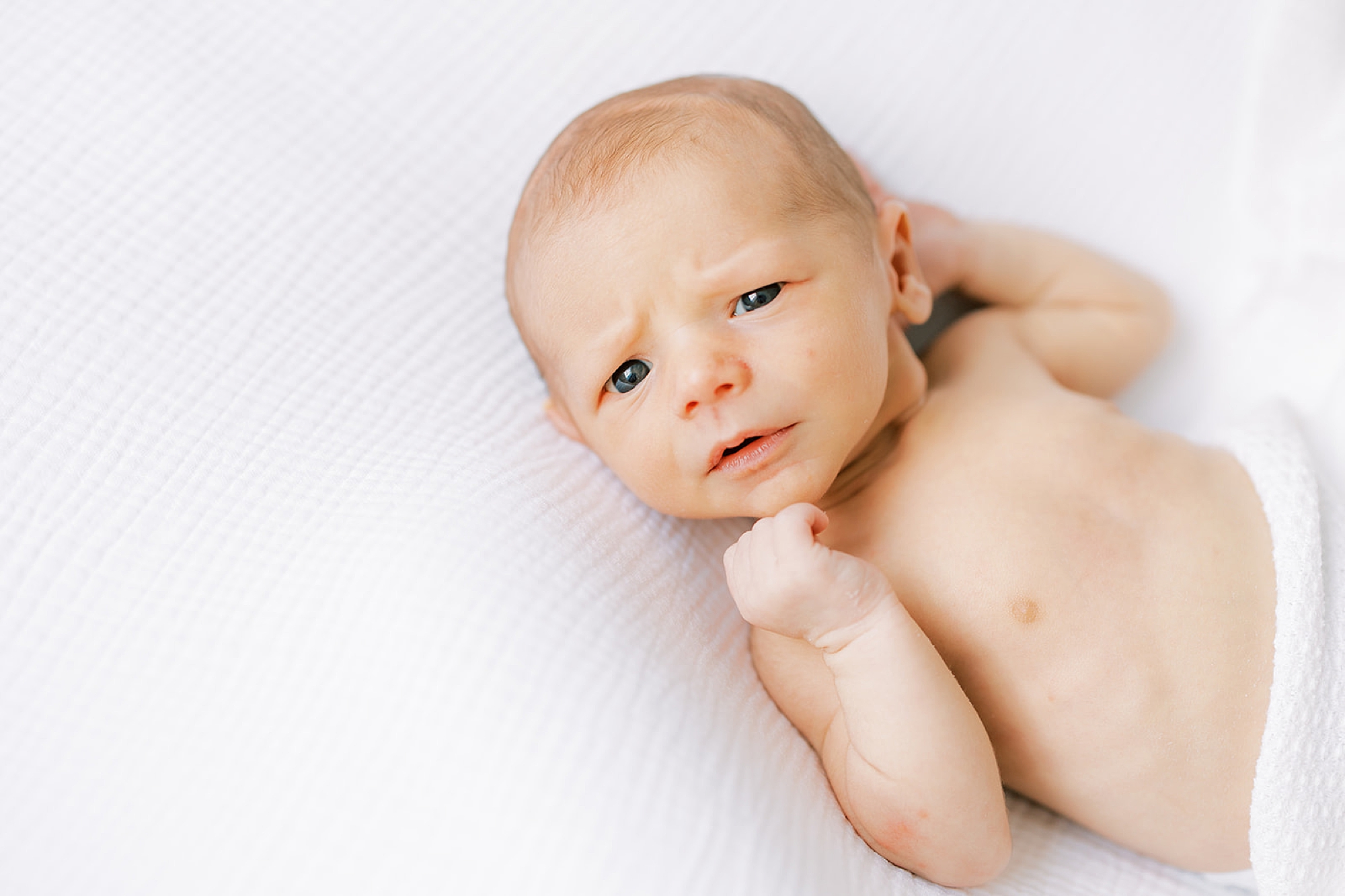 baby boy lays on white blanket during studio newborn portraits in Media PA