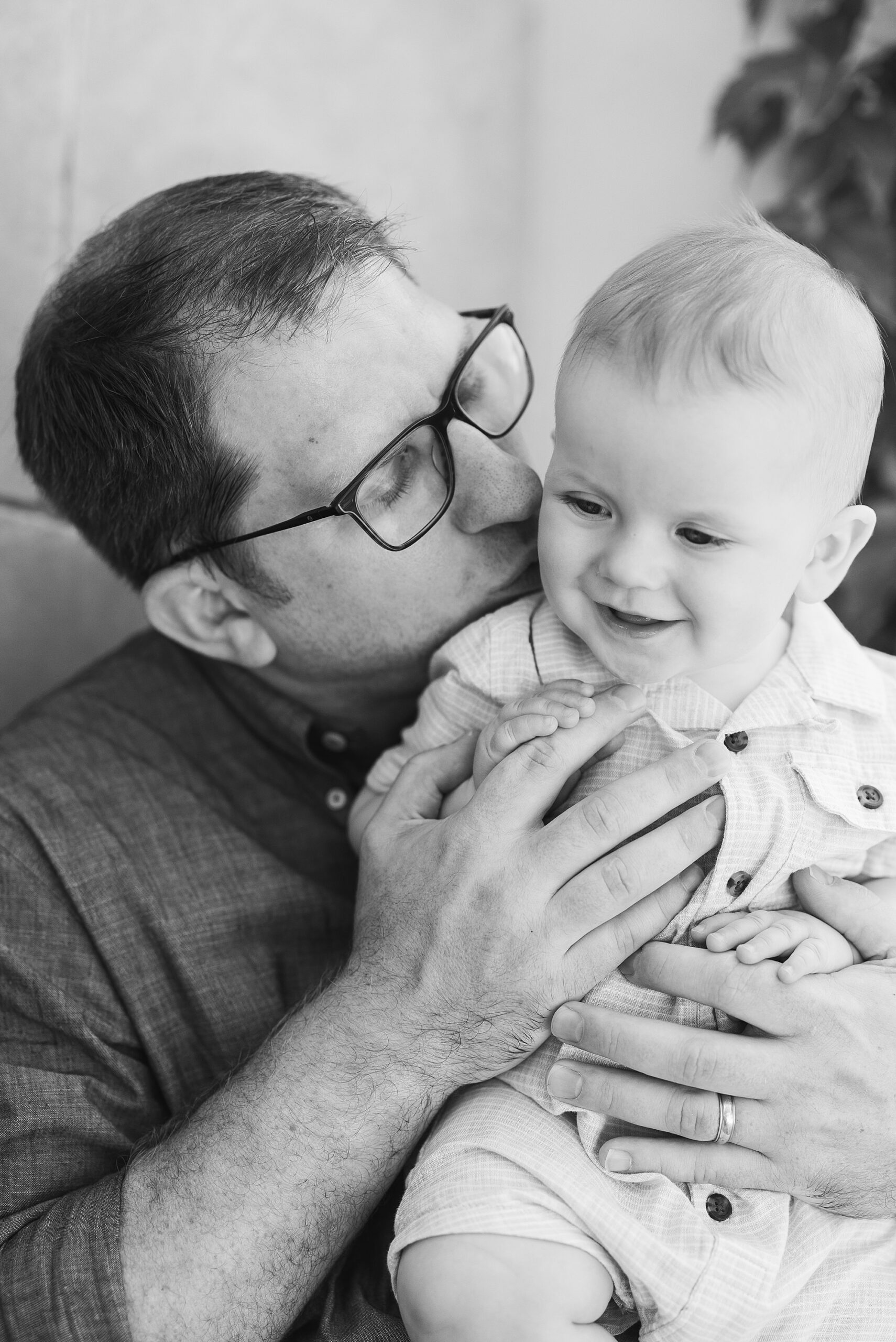 black and white photo of dad kissing son's cheek during Longwood Gardens family photography session 