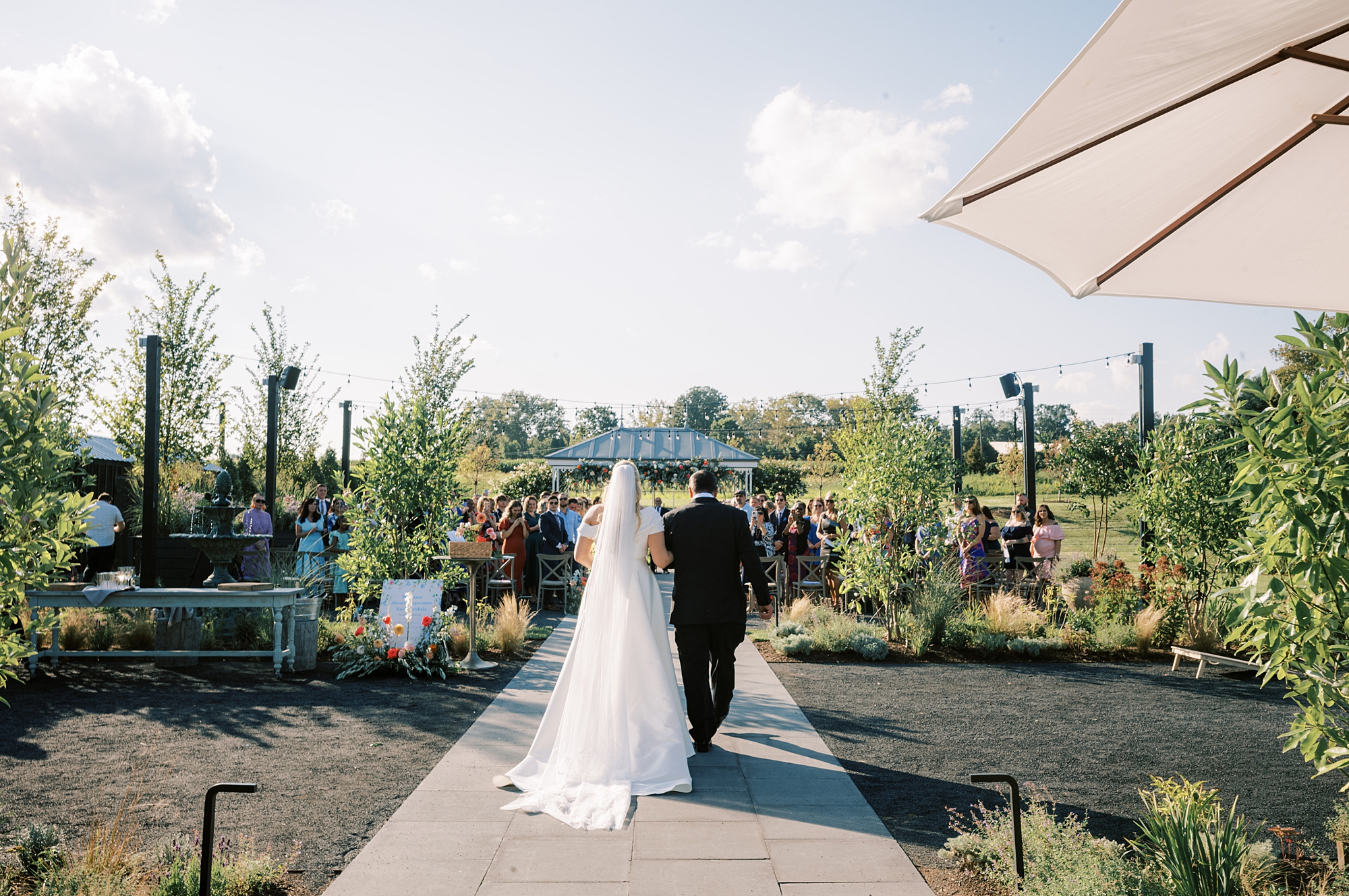 bride and father walk down aisle for ceremony in garden at Terrain DelVal