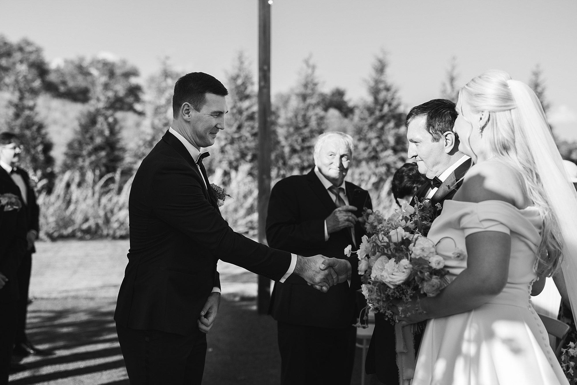 groom reaches to shake hands with bride's father during wedding ceremony in Doylestown PA