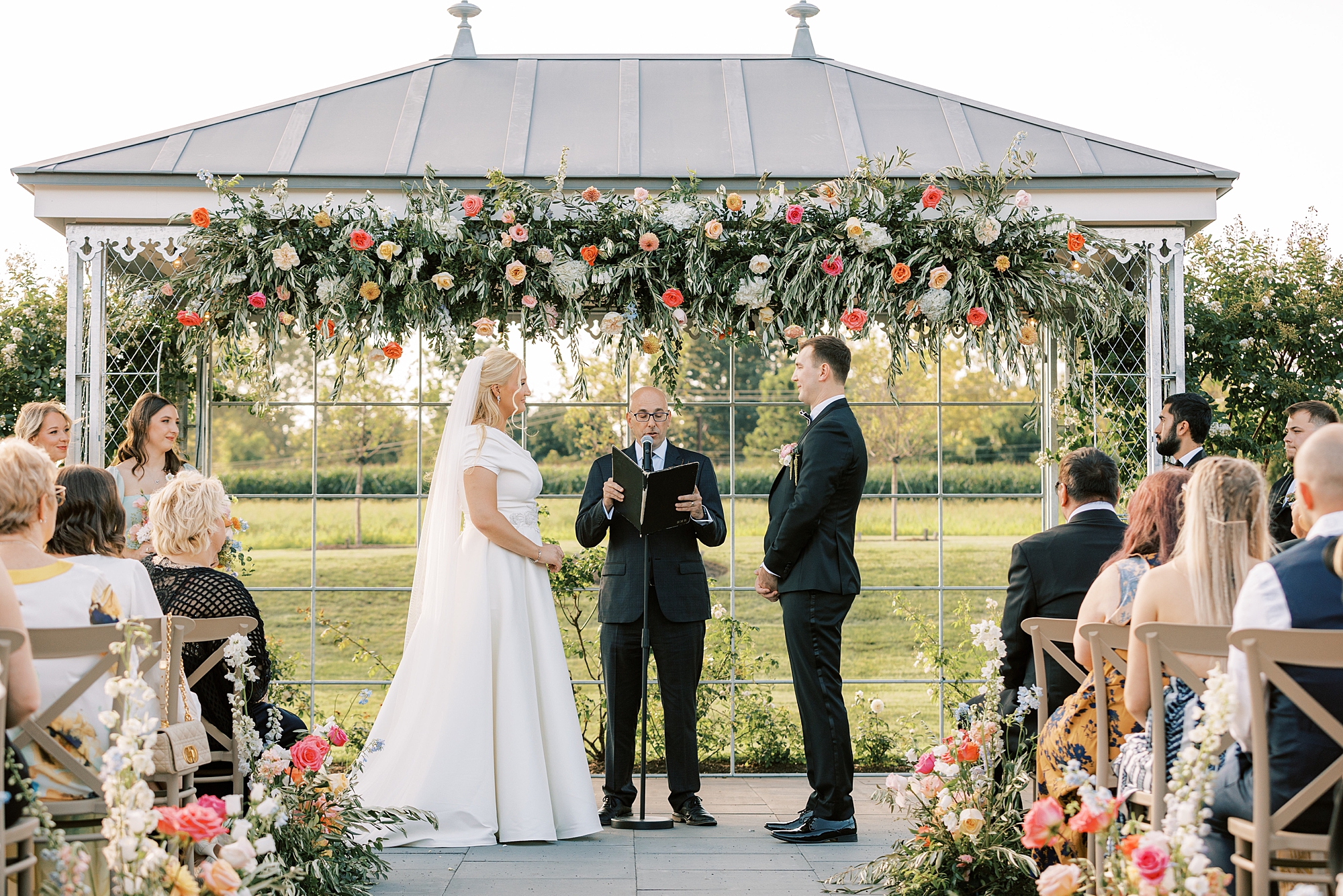 newlyweds exchange vows under arbor during wedding ceremony in Doylestown PA