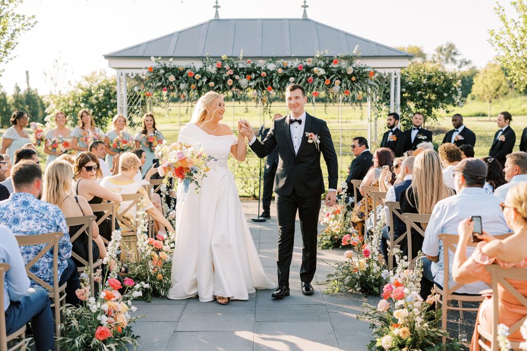 newlyweds hold hands cheering leaving wedding ceremony in Doylestown PA