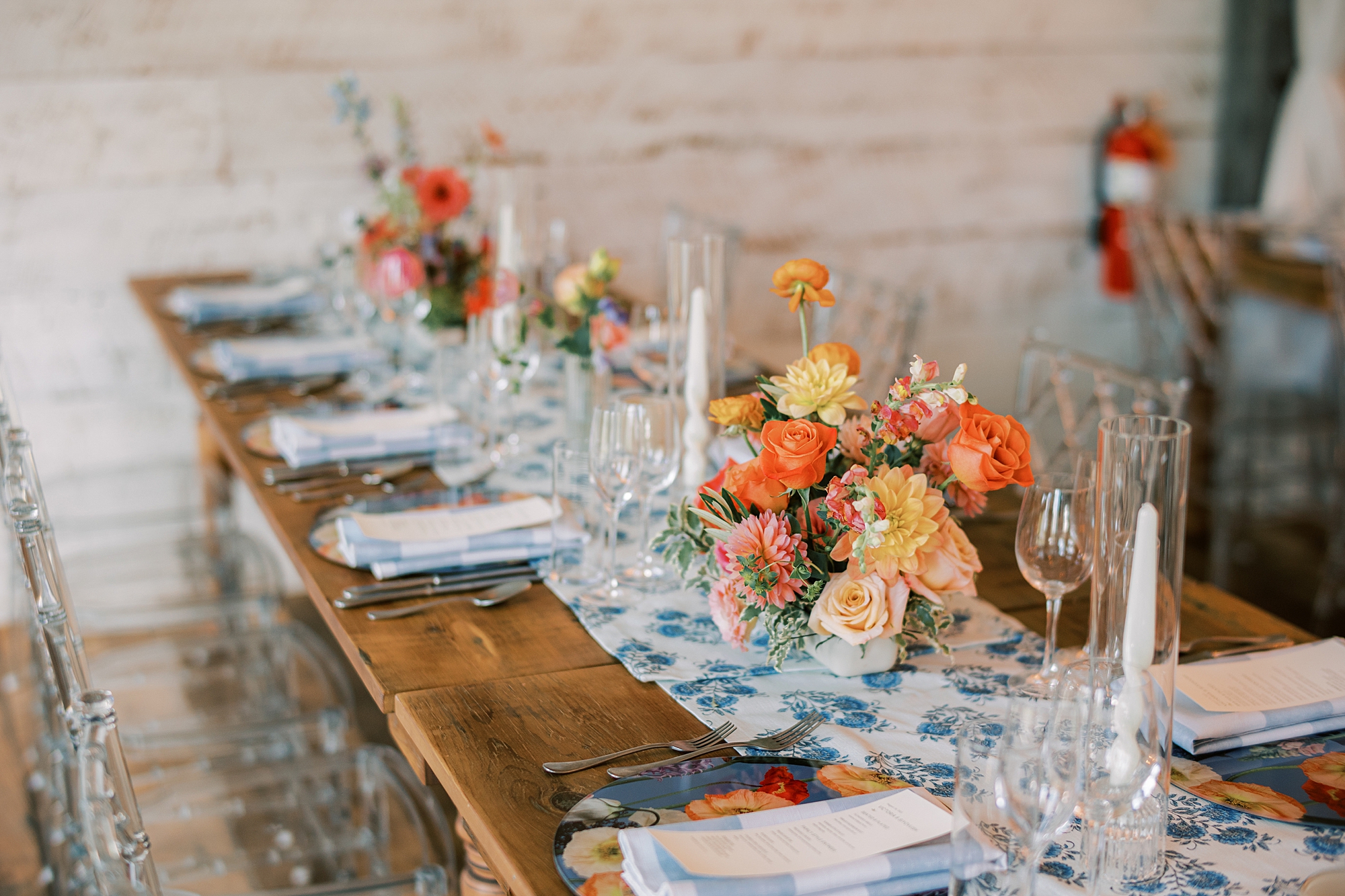 wedding reception with rustic wooden tables, blue and white table runner and bright flower centerpieces at Terrain Gardens