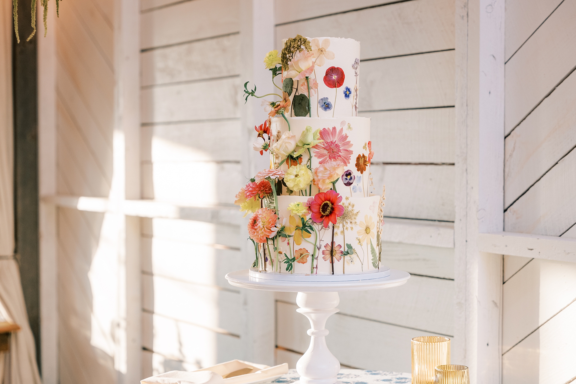 tiered wedding cake on white stand with flower accents 