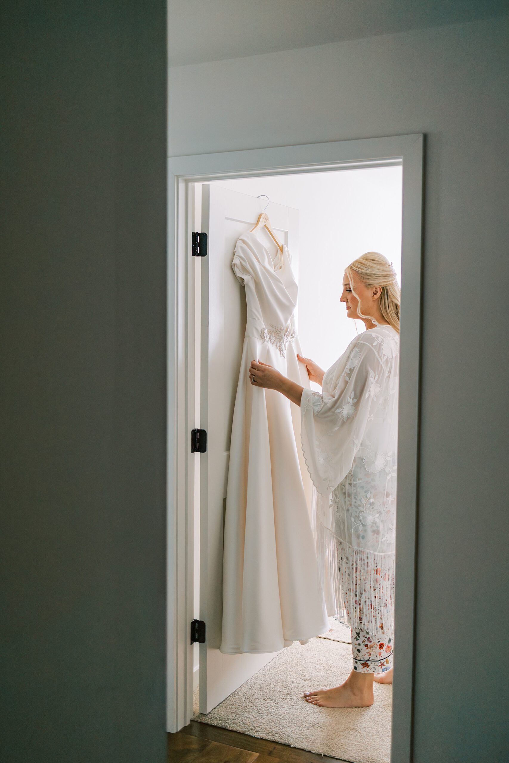 blonde woman looks at wedding dress hanging in suite at Terrain Del-Val