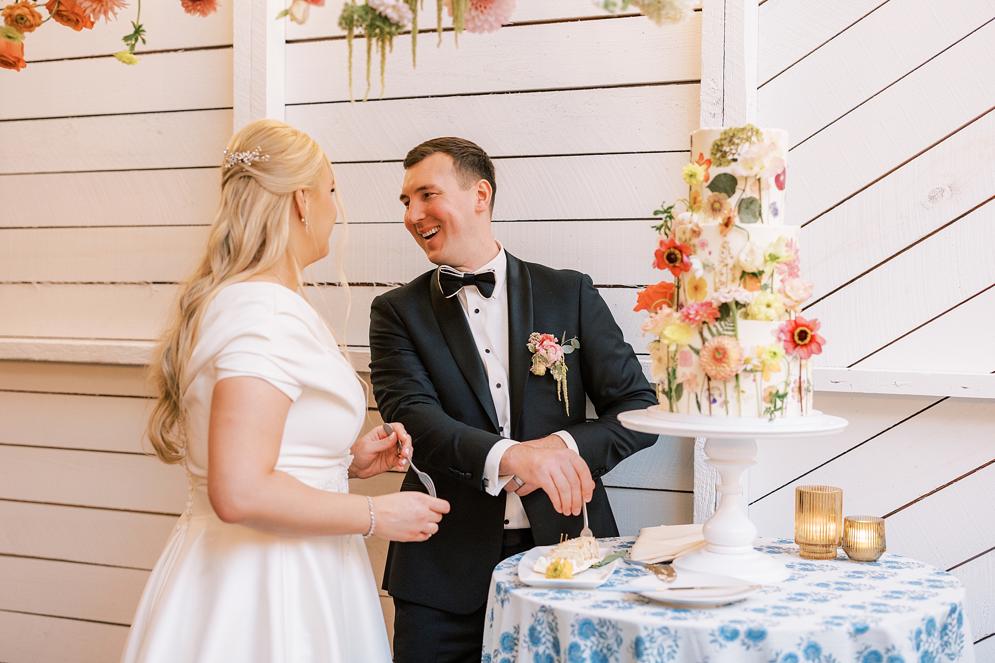 bride and groom smile together during cake cutting at Terrain Gardens wedding reception