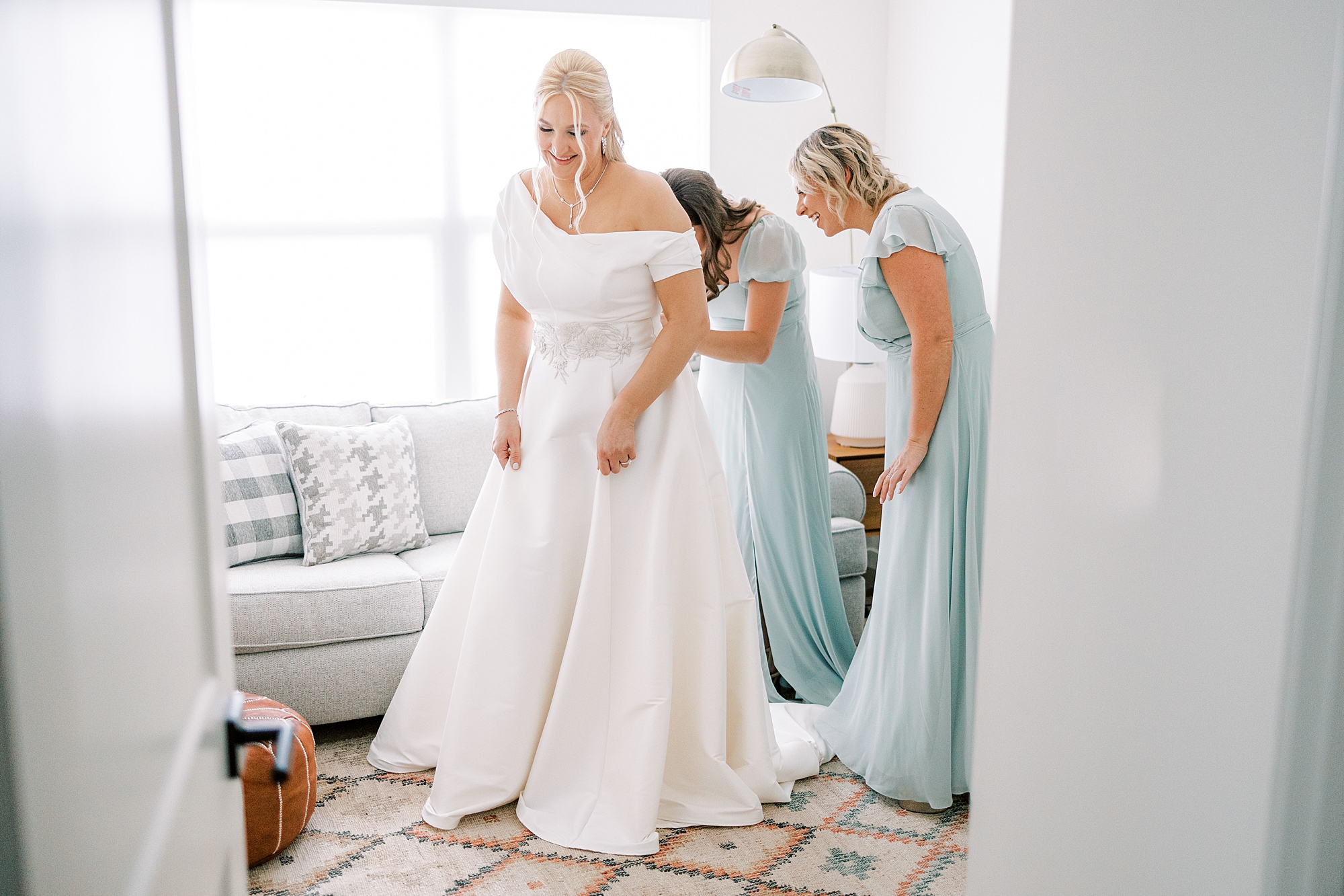 bridesmaids help bride into wedding dress in suite at Terrain DelVal