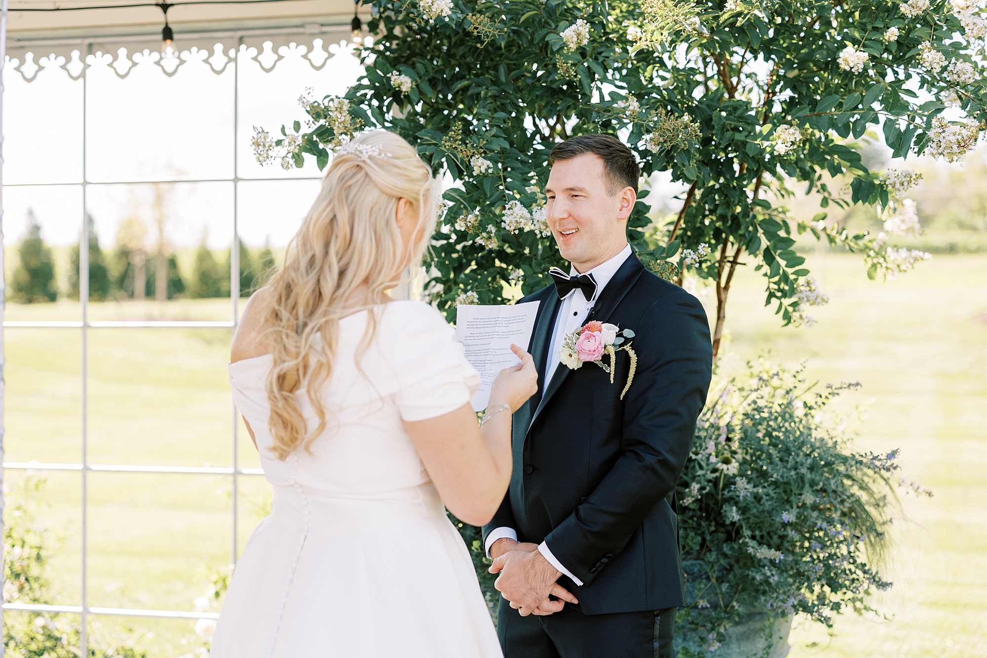 groom and bride read vow booklets during first look together on wedding day