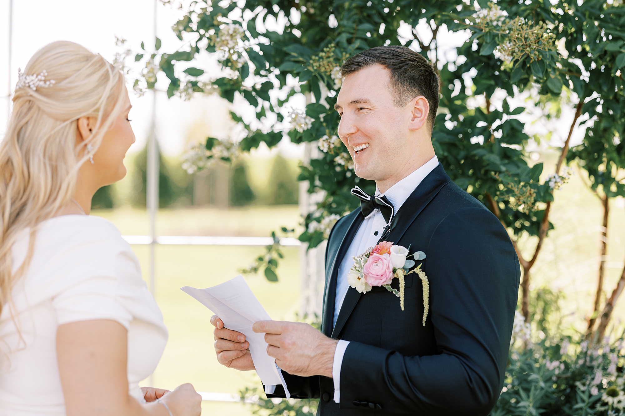 groom smiles reading vows to bride on wedding day 