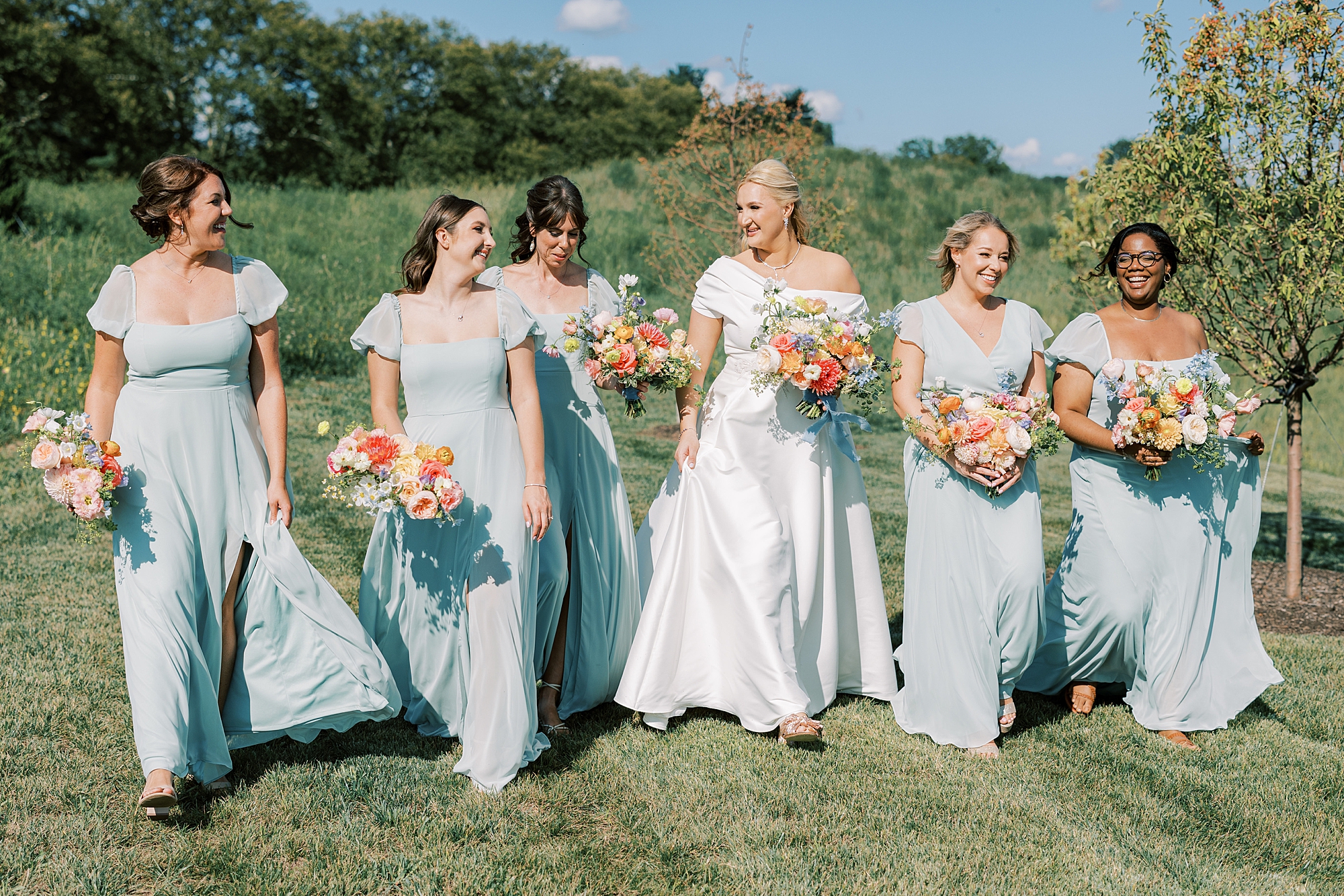 bride walks with bridesmaids in light blue gowns during PA wedding day 