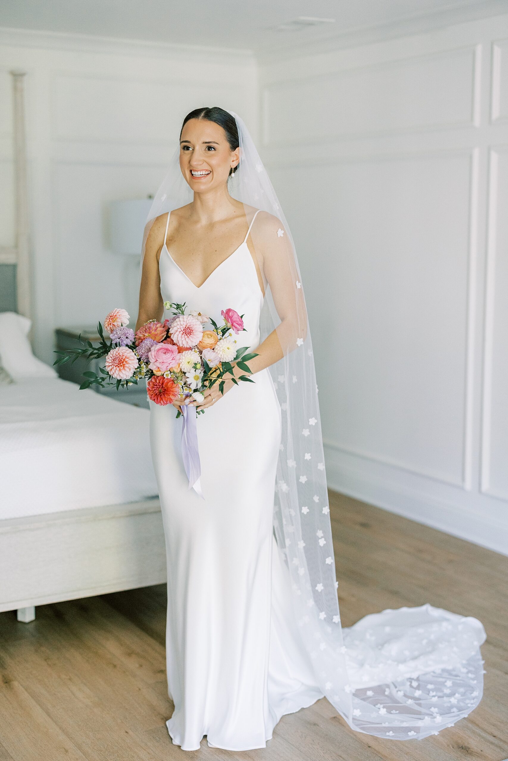 bride stands holding bouquet of pink and white roses 
