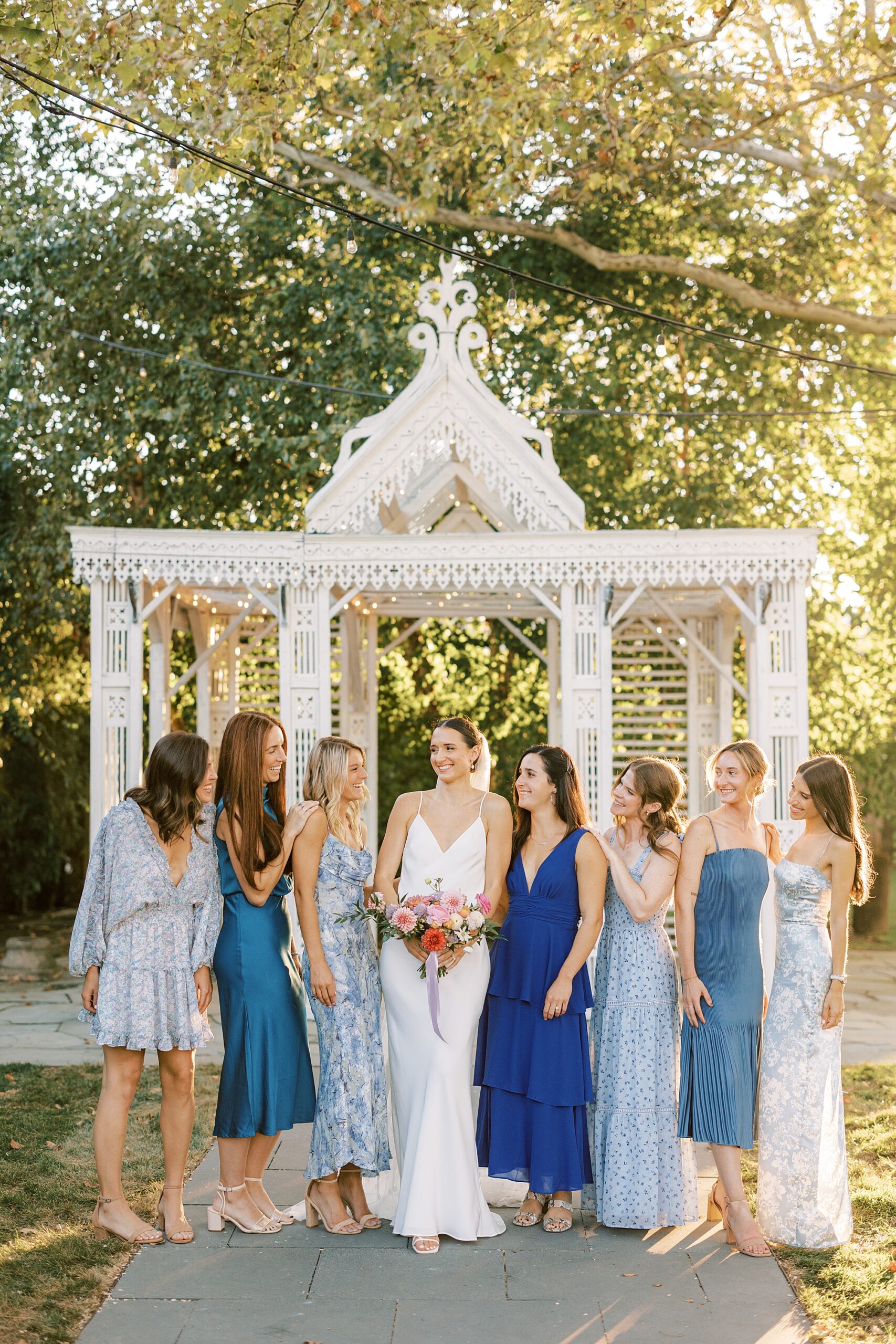 bride poses with bridesmaids in various blue dresses