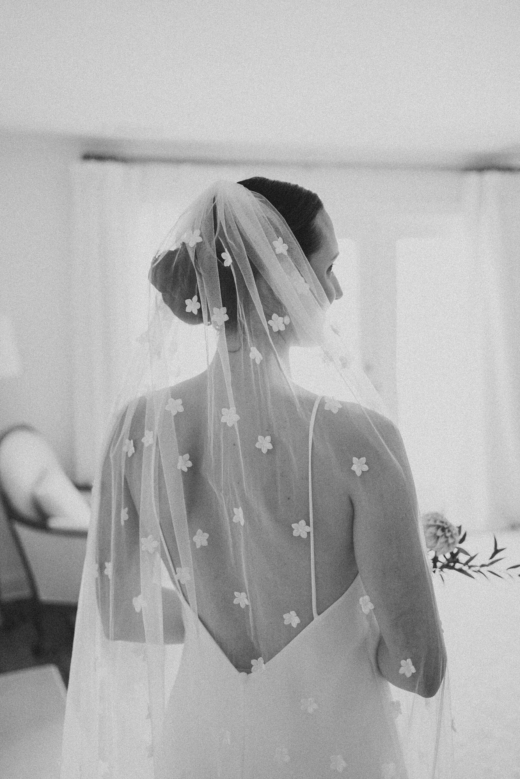 bride stands with veil down her back with floral accents 