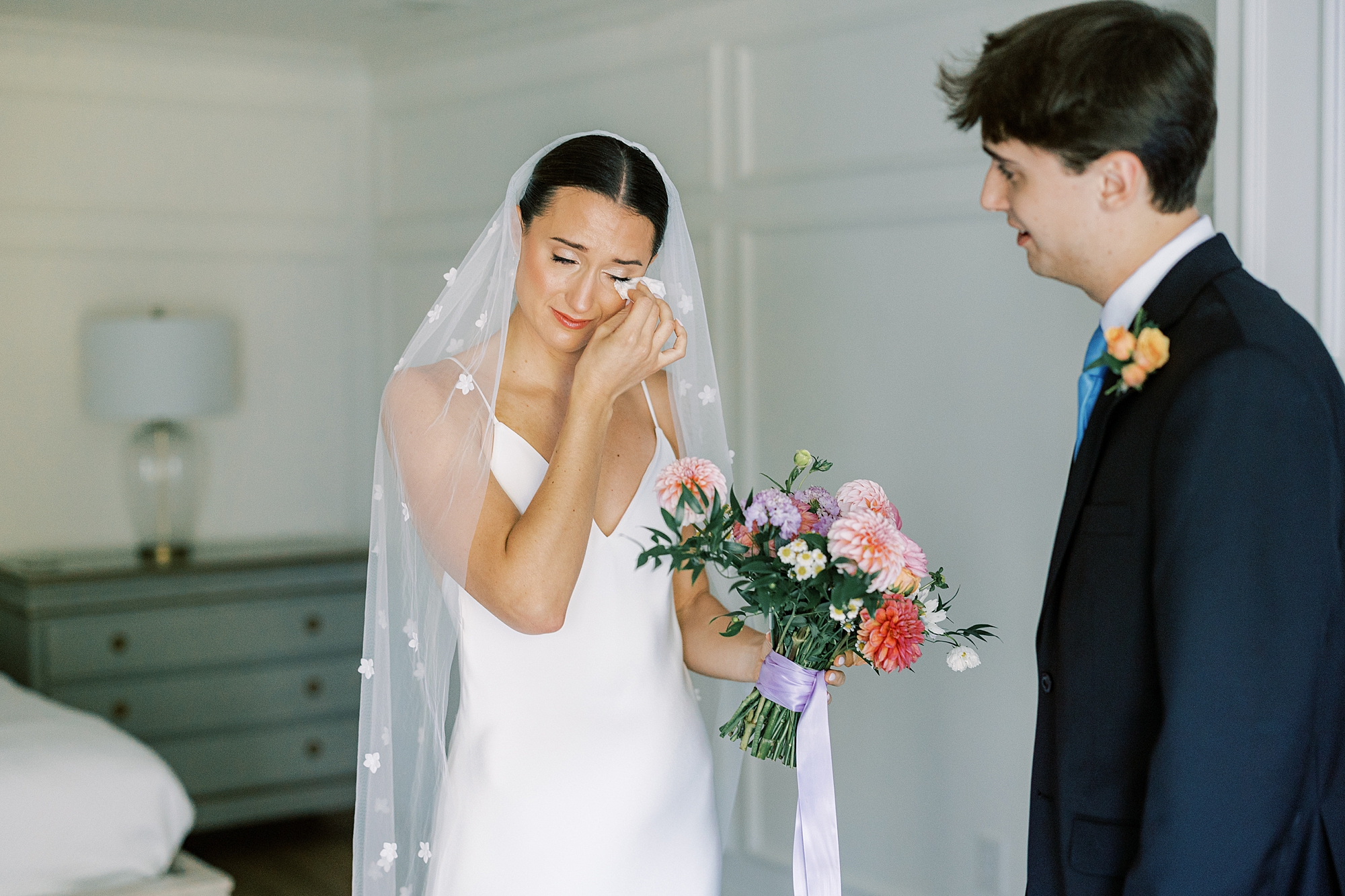 bride wipes away tear during first look at fireplace at Fairville Inn in Chadds Ford