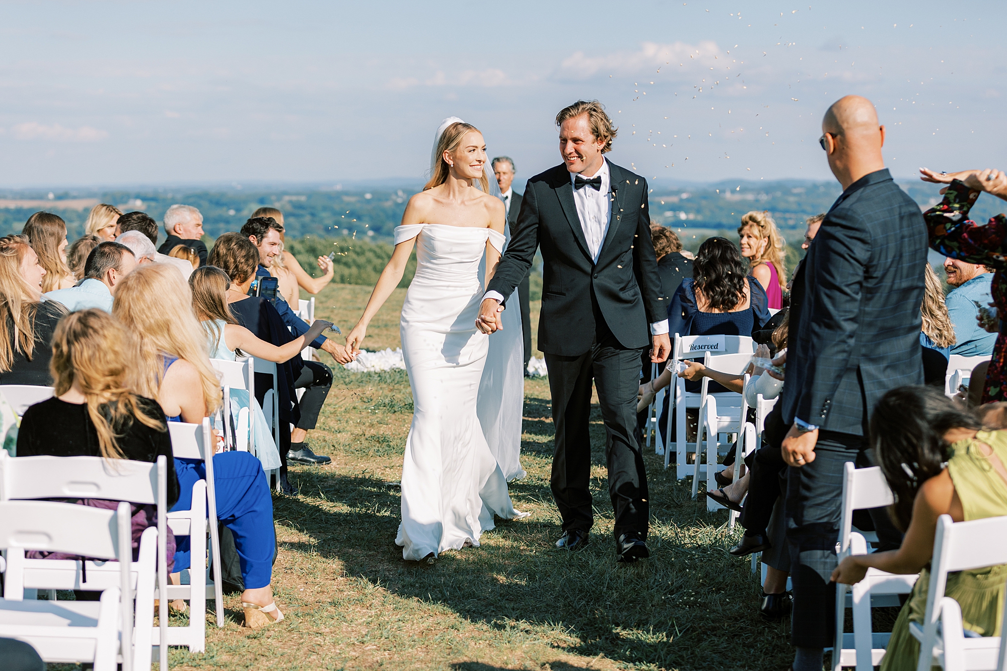 bride and groom hold hands walking up aisle after Lauxmont Farms wedding ceremony 